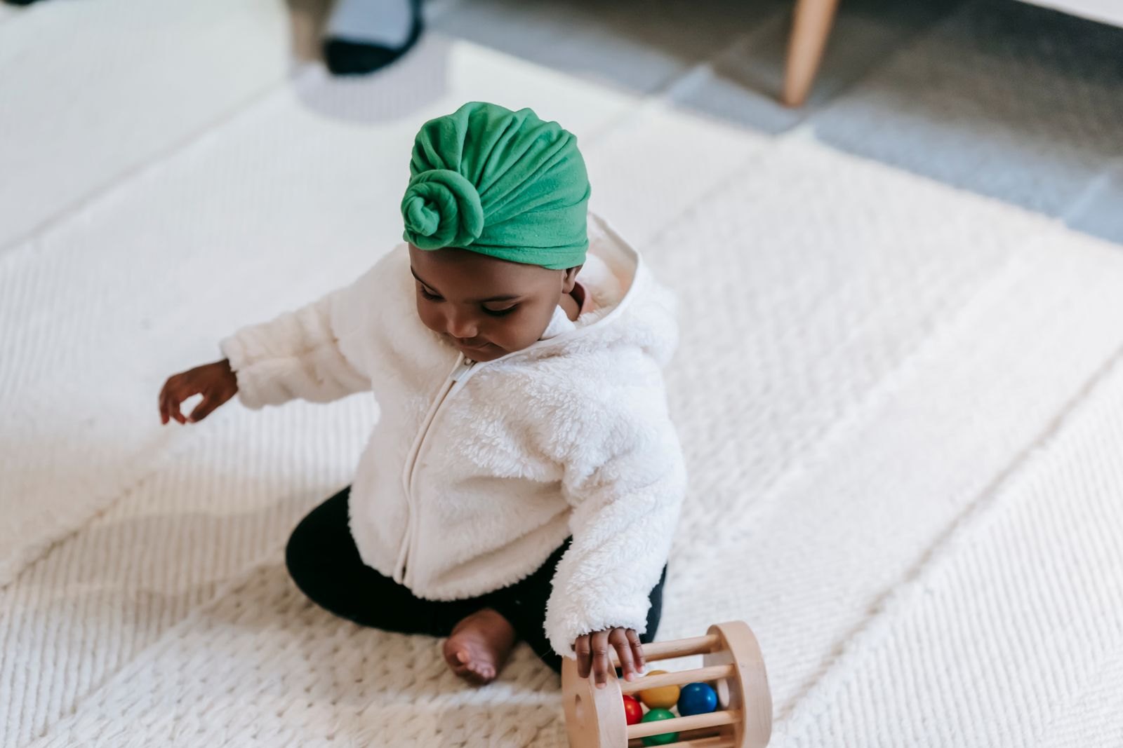 Baby sitzt vertieft auf dem Boden und spielt mit einem Holz-Rollspielzeug, ohne aufzuschauen