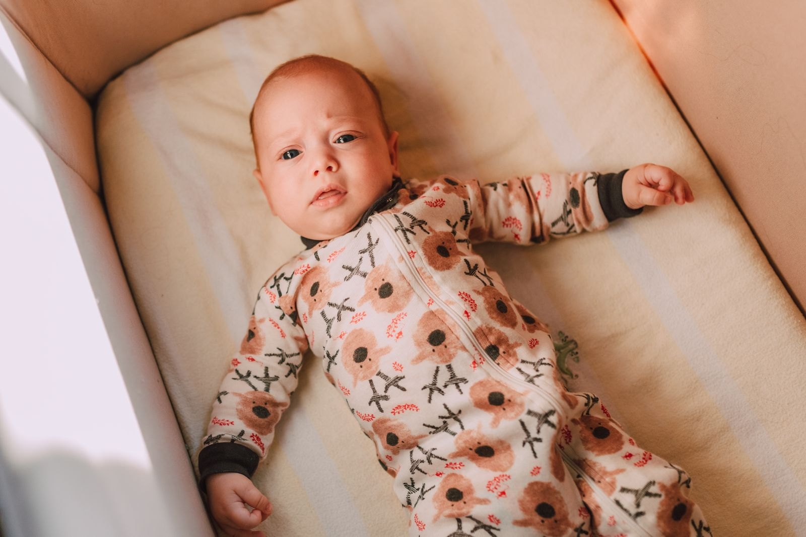 Ein Baby liegt im warmen Morgenlicht in seinem Bettchen