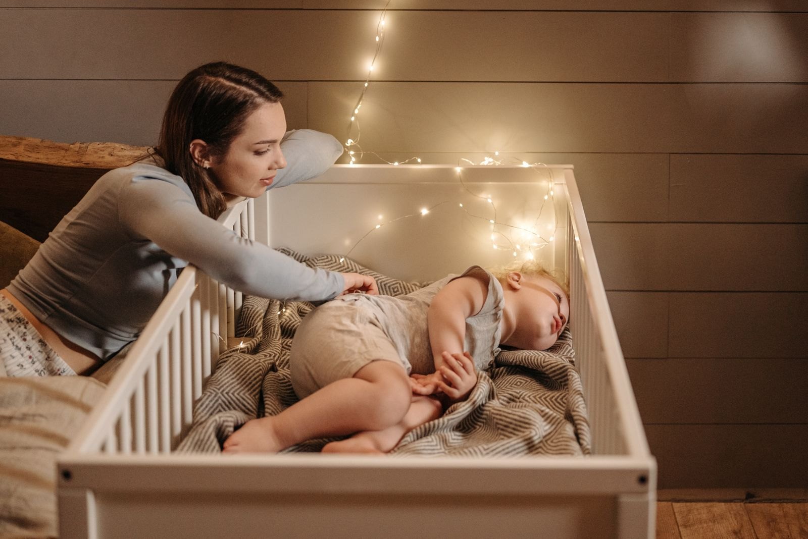 A parent checking on a baby who has woken in a dim nursery at night