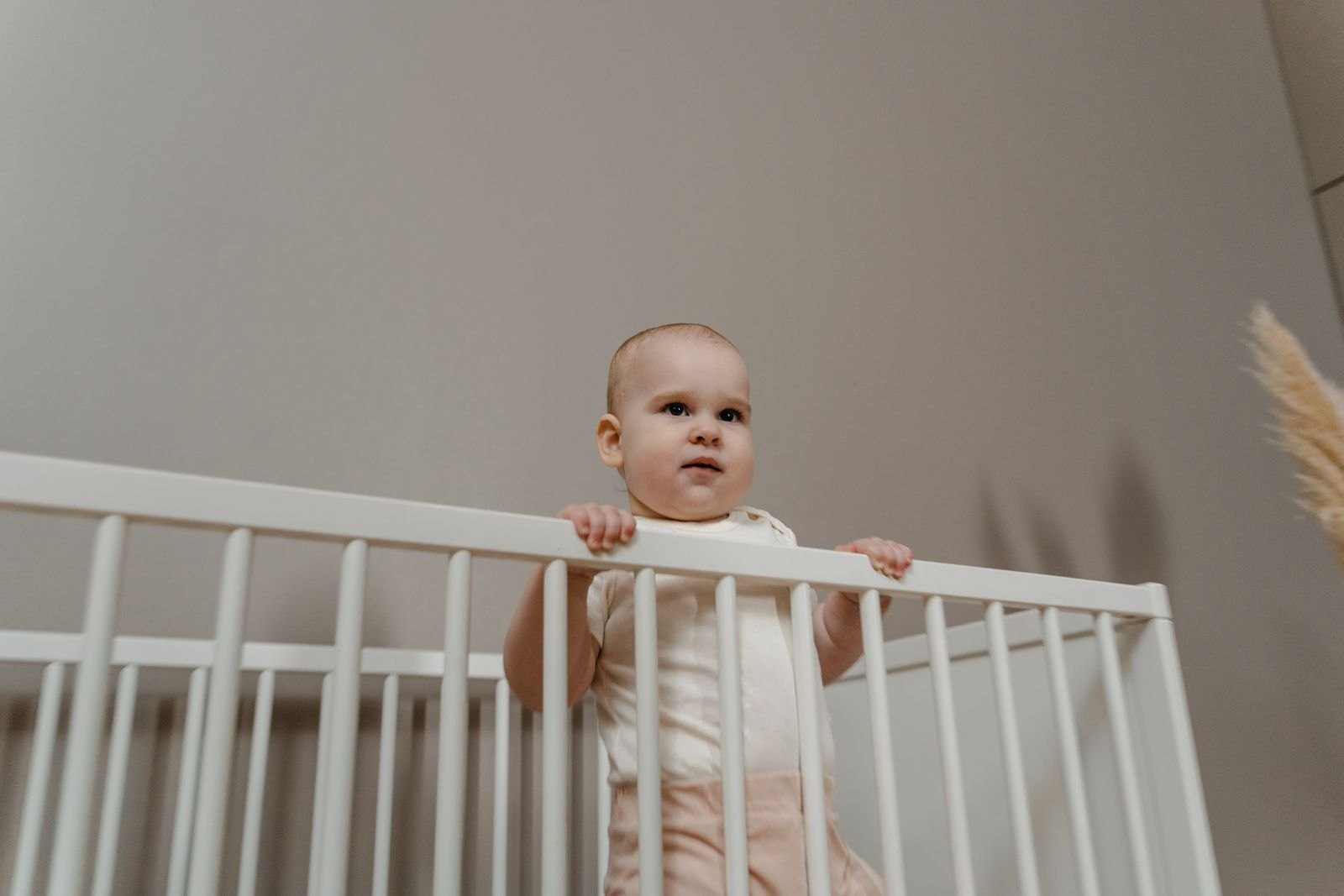 A baby standing in a crib at night, holding onto the rail
