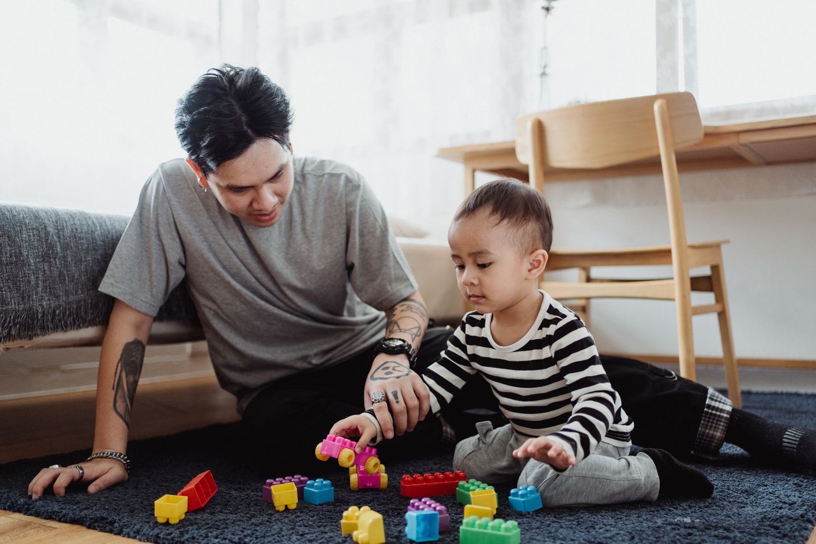 A father playing with his toddler on the living room floor