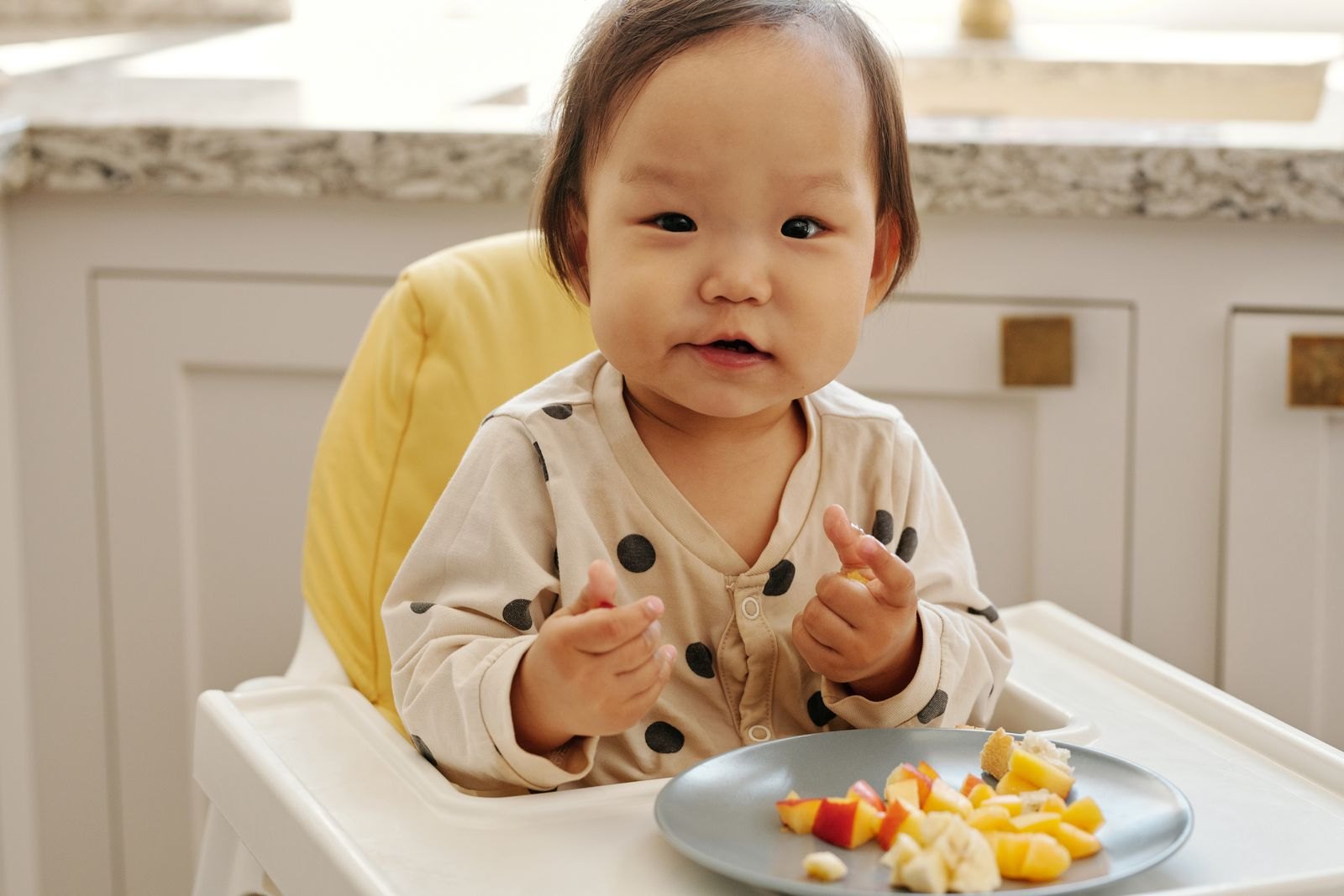 A baby self-feeding a soft, graspable piece of food, a baby-led weaning approach