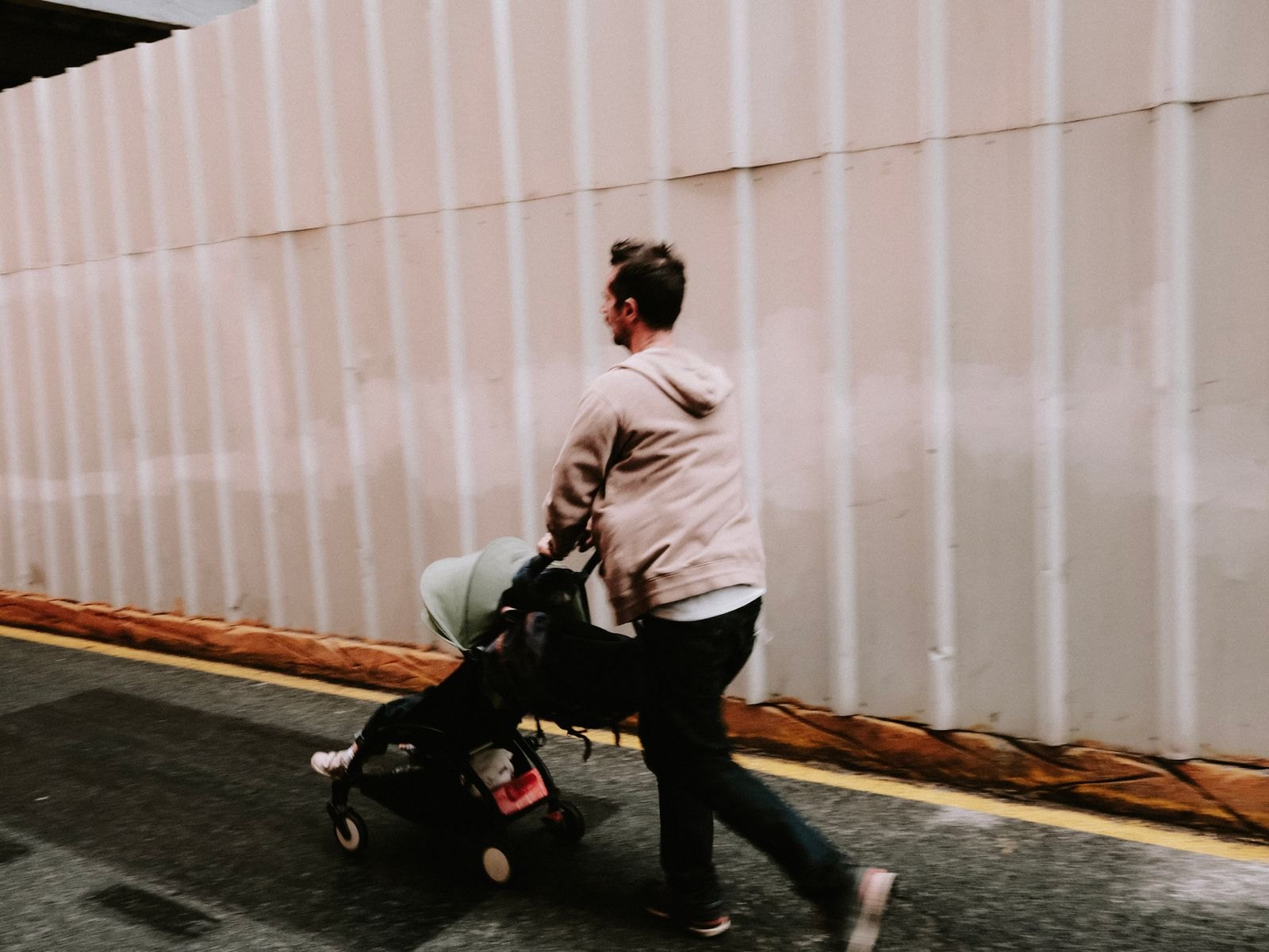 A parent walking briskly while pushing a modern stroller outdoors