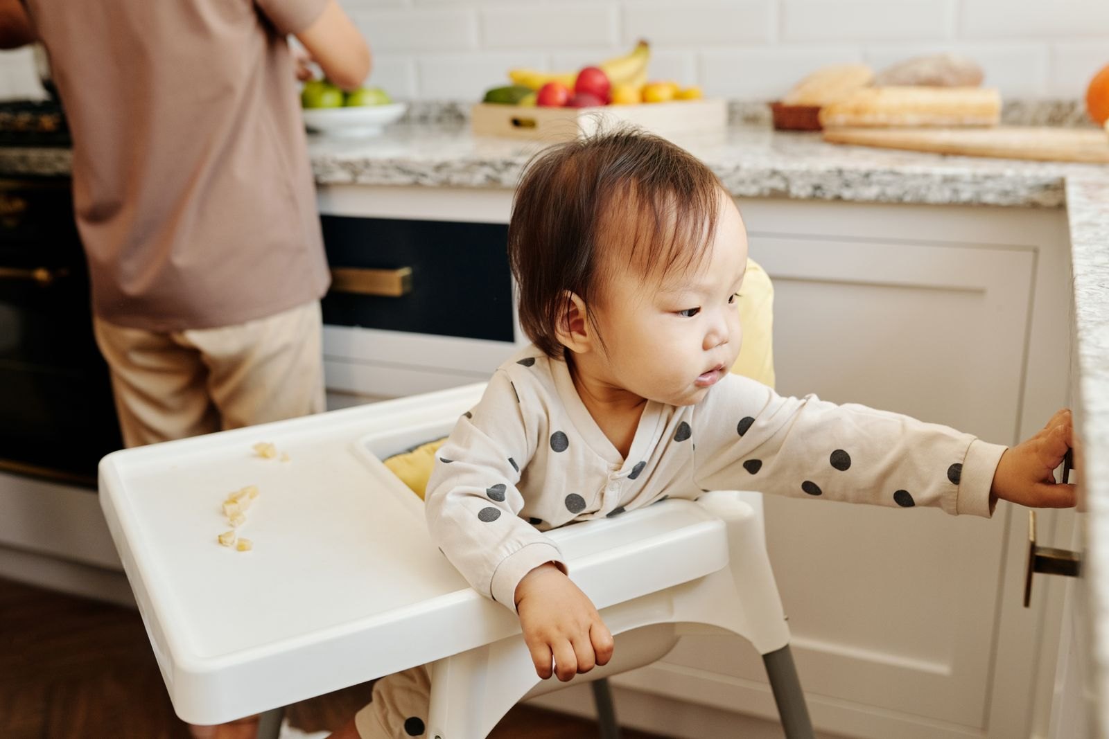 A baby reaching toward a parent who is stepping out of the room