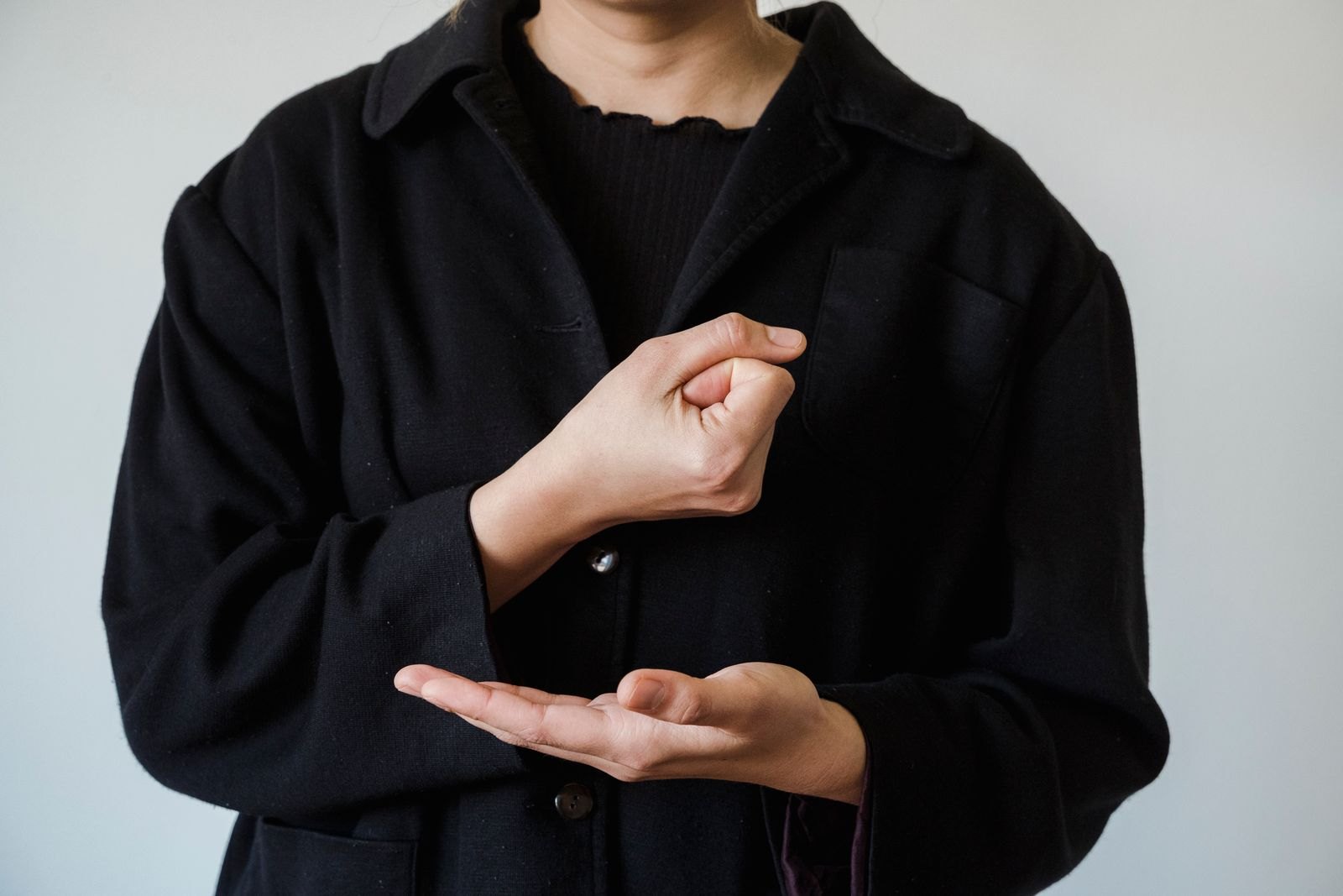 A parent making a simple hand sign while speaking the matching word to their baby