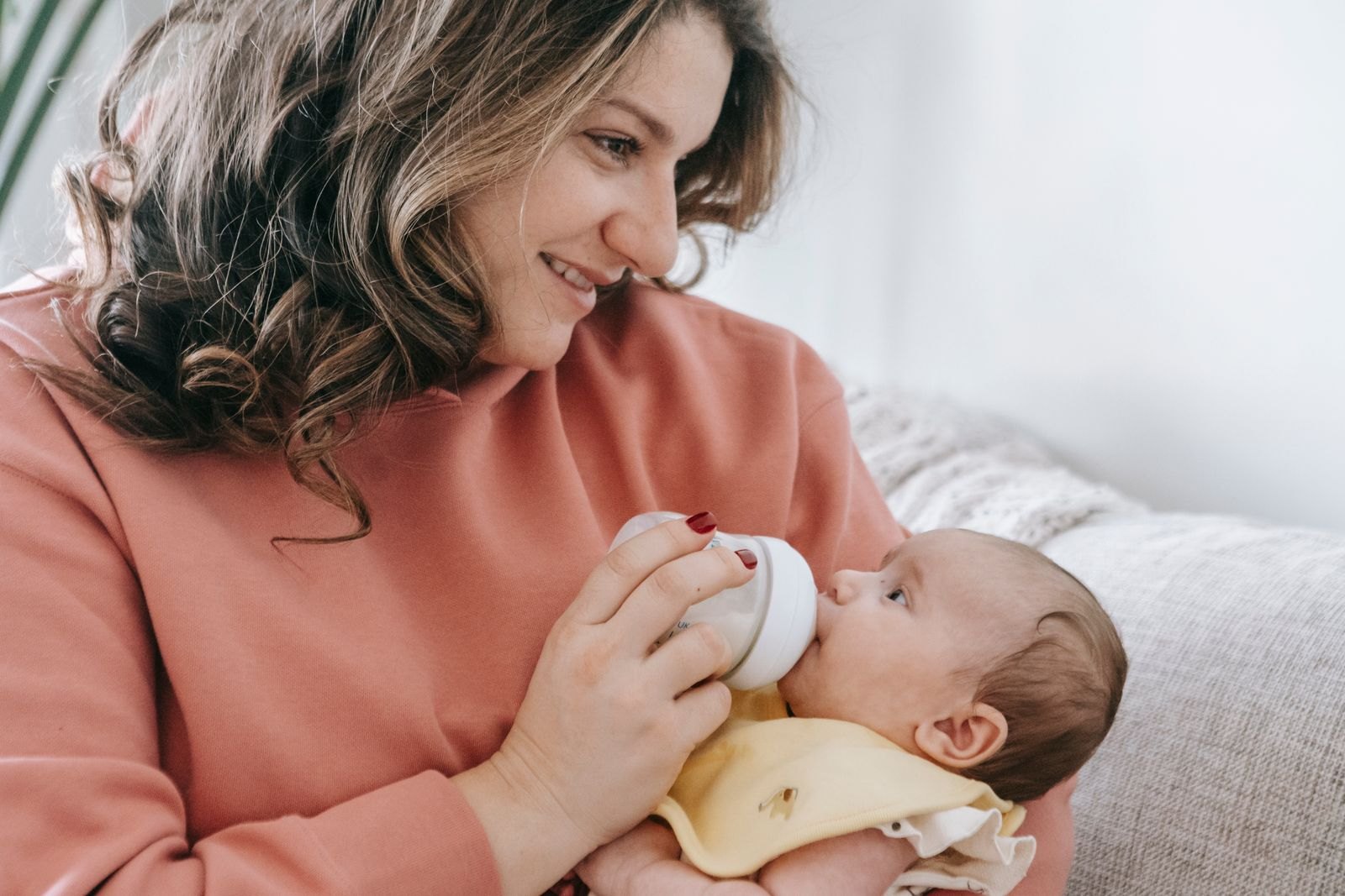 A parent bottle-feeding a baby while holding them close and upright