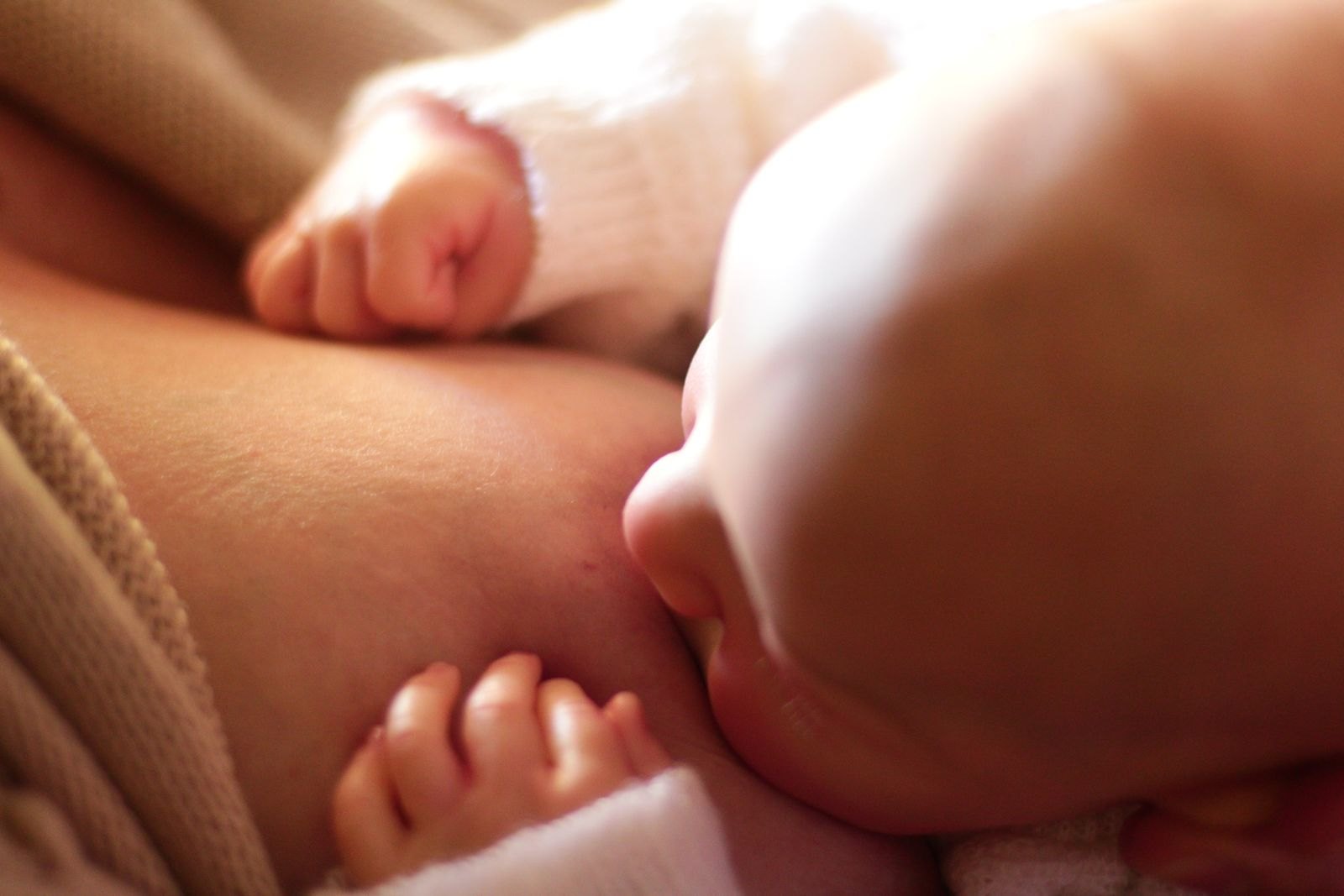 A close-up of a newborn breastfeeding, calm and settled