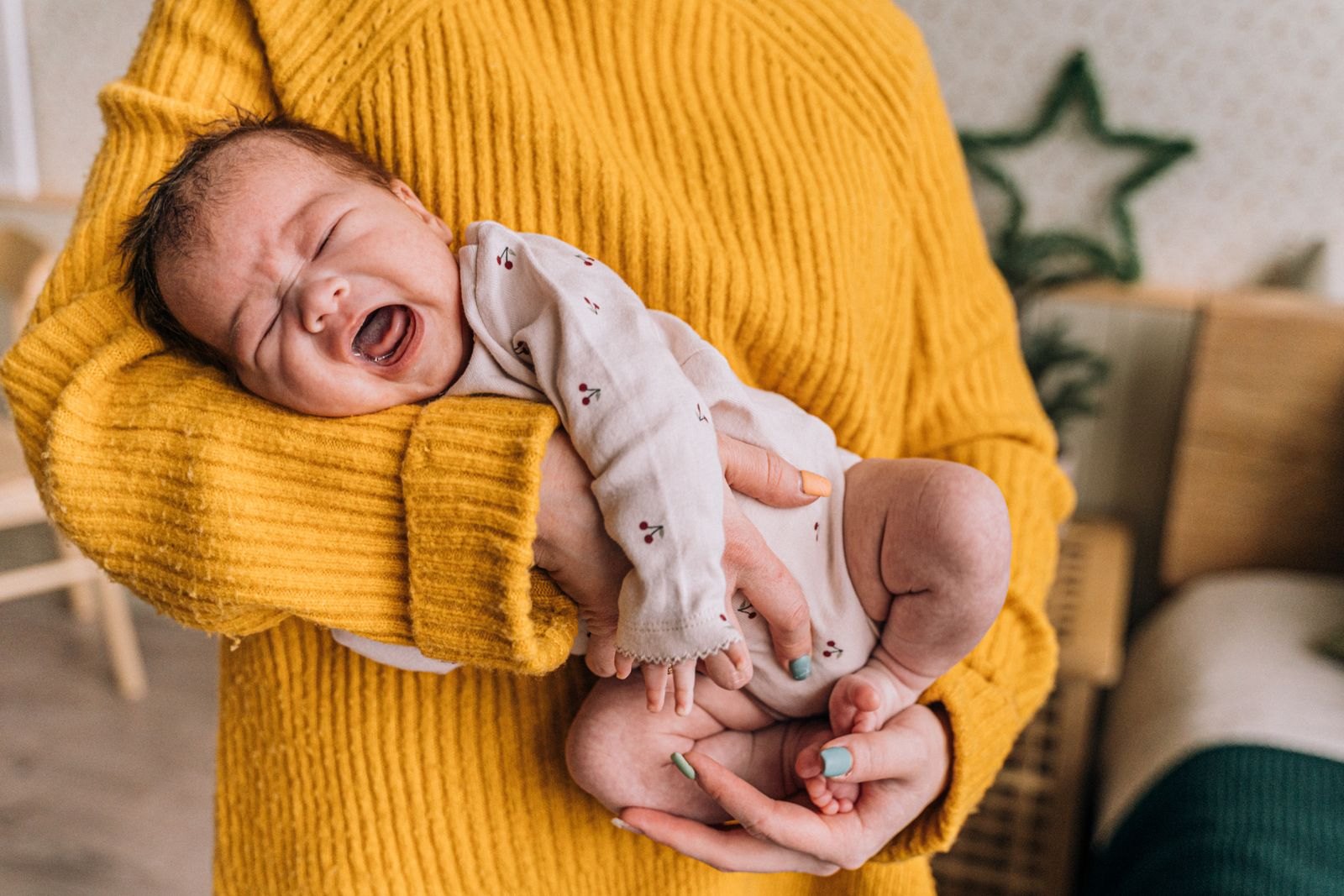 A parent comforting a crying newborn baby at home