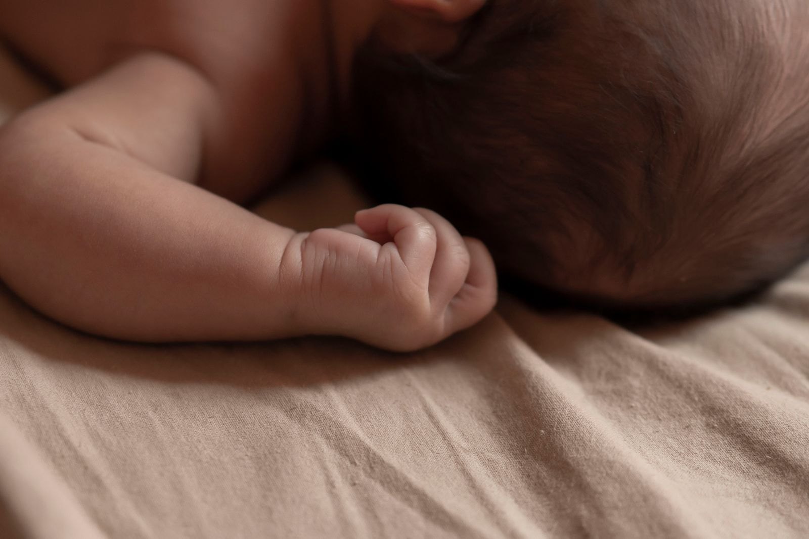 A newborn crying while being comforted and held by a parent
