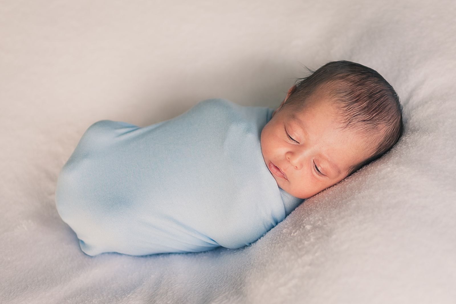 A newborn baby swaddled and sleeping peacefully