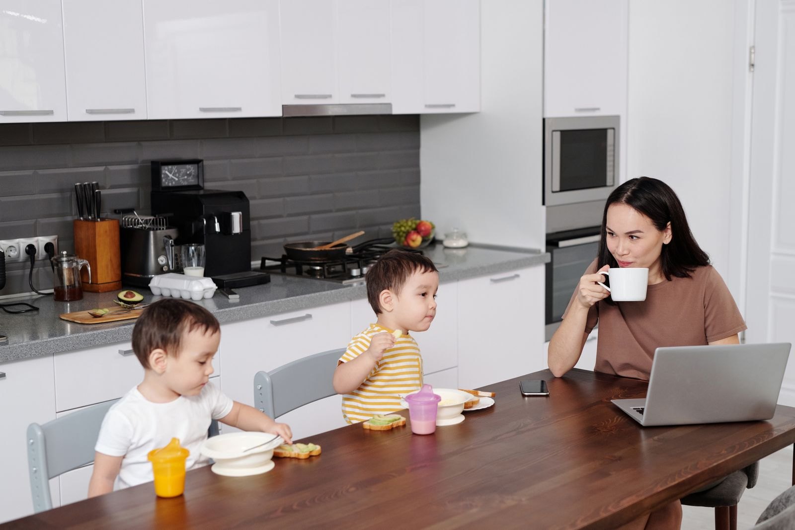 A mother on a phone call while sitting with her toddler at home