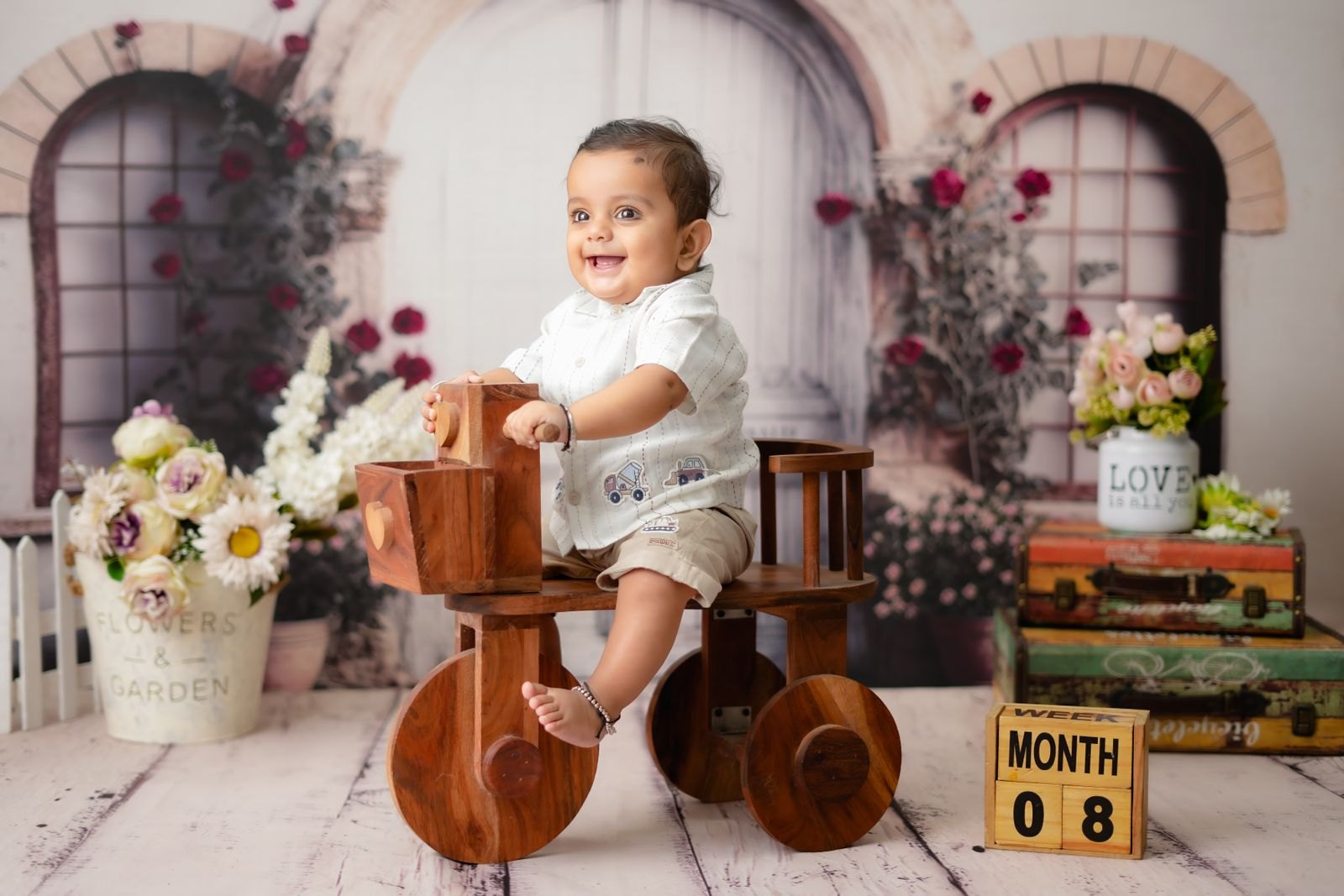 An 8-month-old baby smiling and sitting up during a photo session