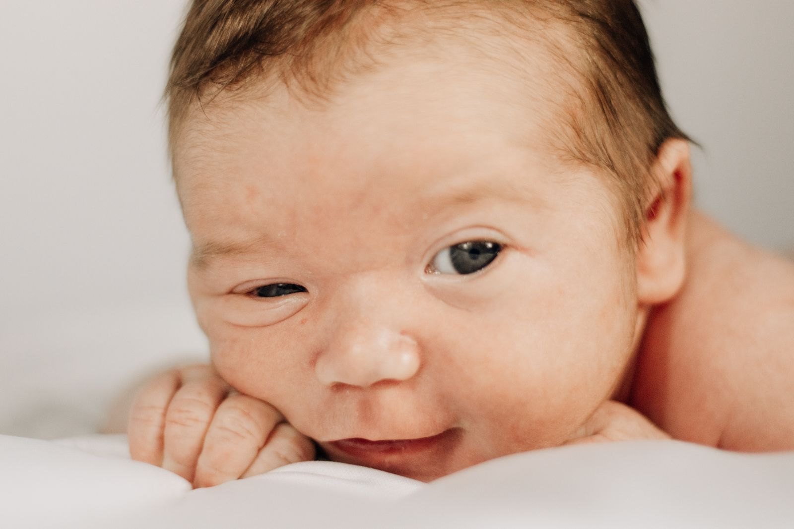 A close-up of a sleepy newborn resting on a blanket
