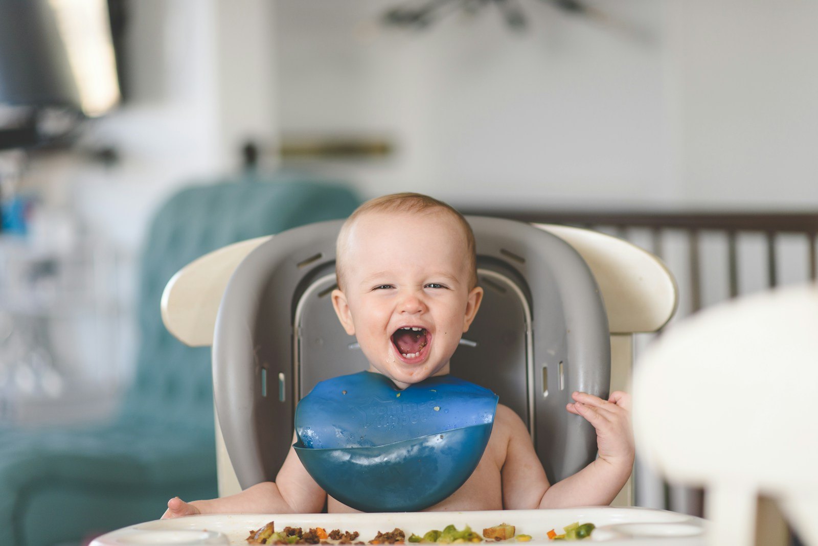 A toddler in a high chair showing reluctance to eat a new food