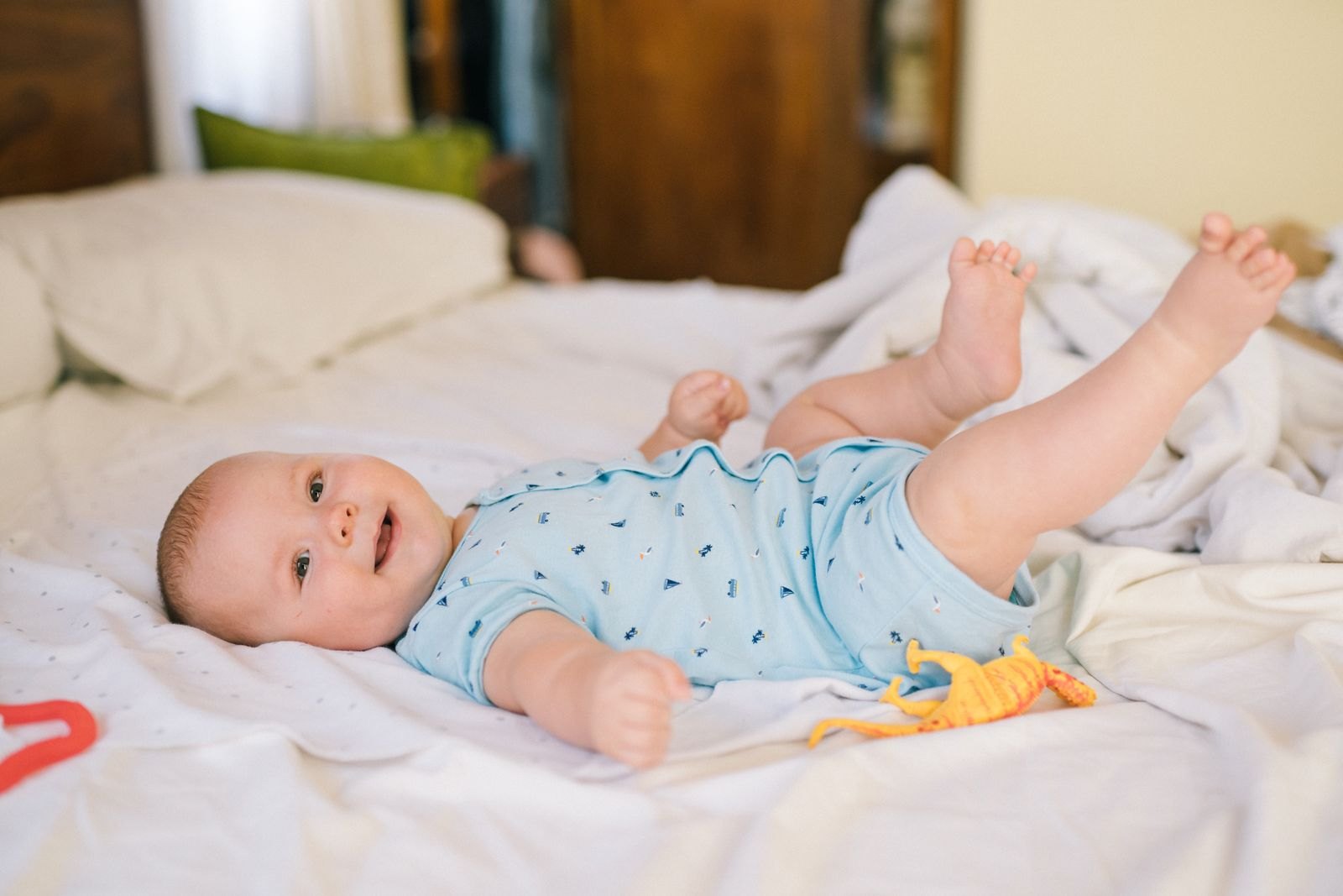 A baby lying on a bed, awake and playful, not showing any sign of being ready to sleep