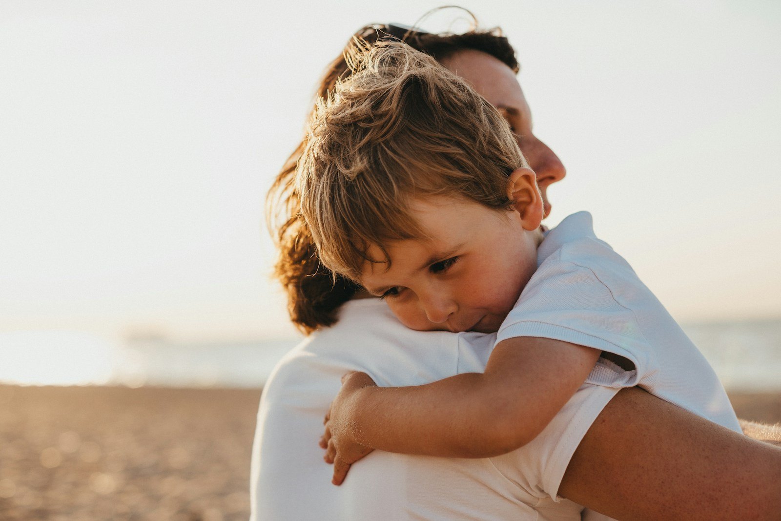 A parent kneeling calmly beside an upset toddler, offering comfort during a meltdown