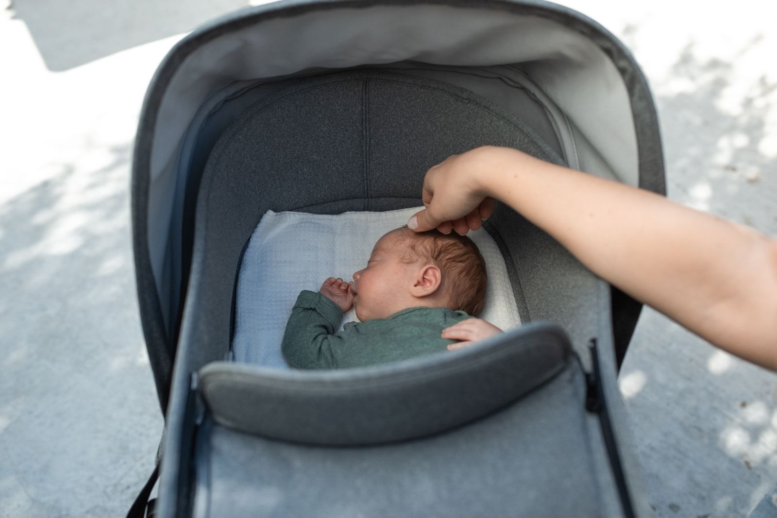 Una madre acaricia con suavidad la parte de atrás de la cabeza de su bebé dormido en el cochecito