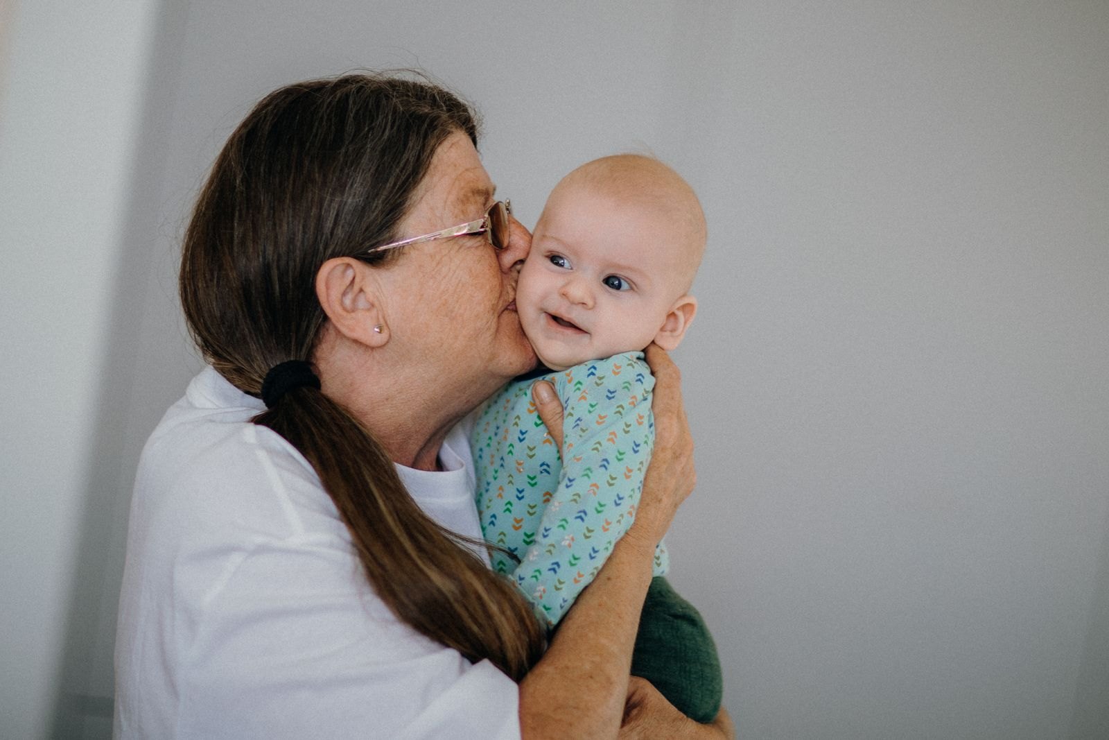 Una abuela abraza y besa a su bebé, que la mira con una sonrisa tranquila