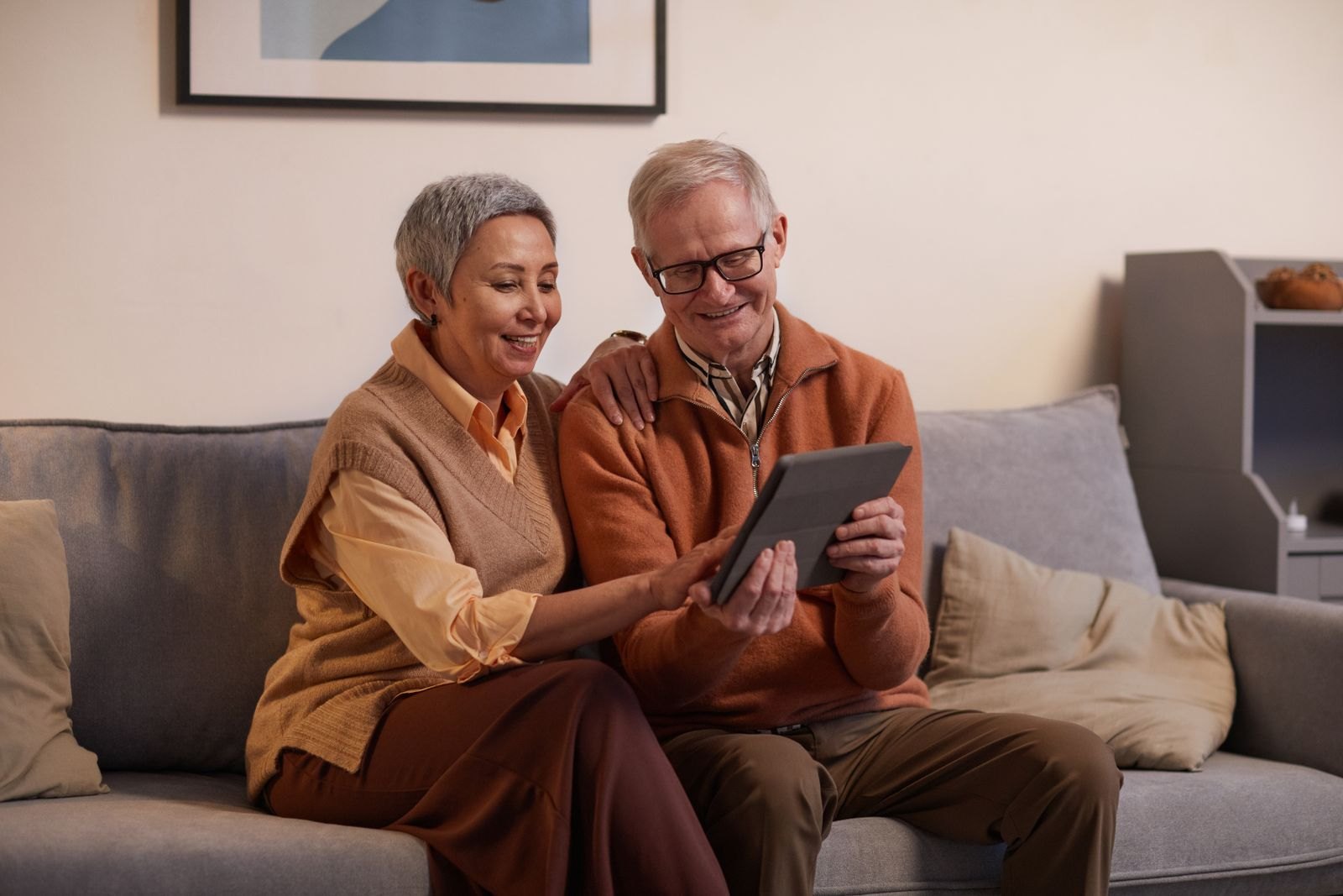 Dos abuelos sonríen mirando una tablet durante una videollamada