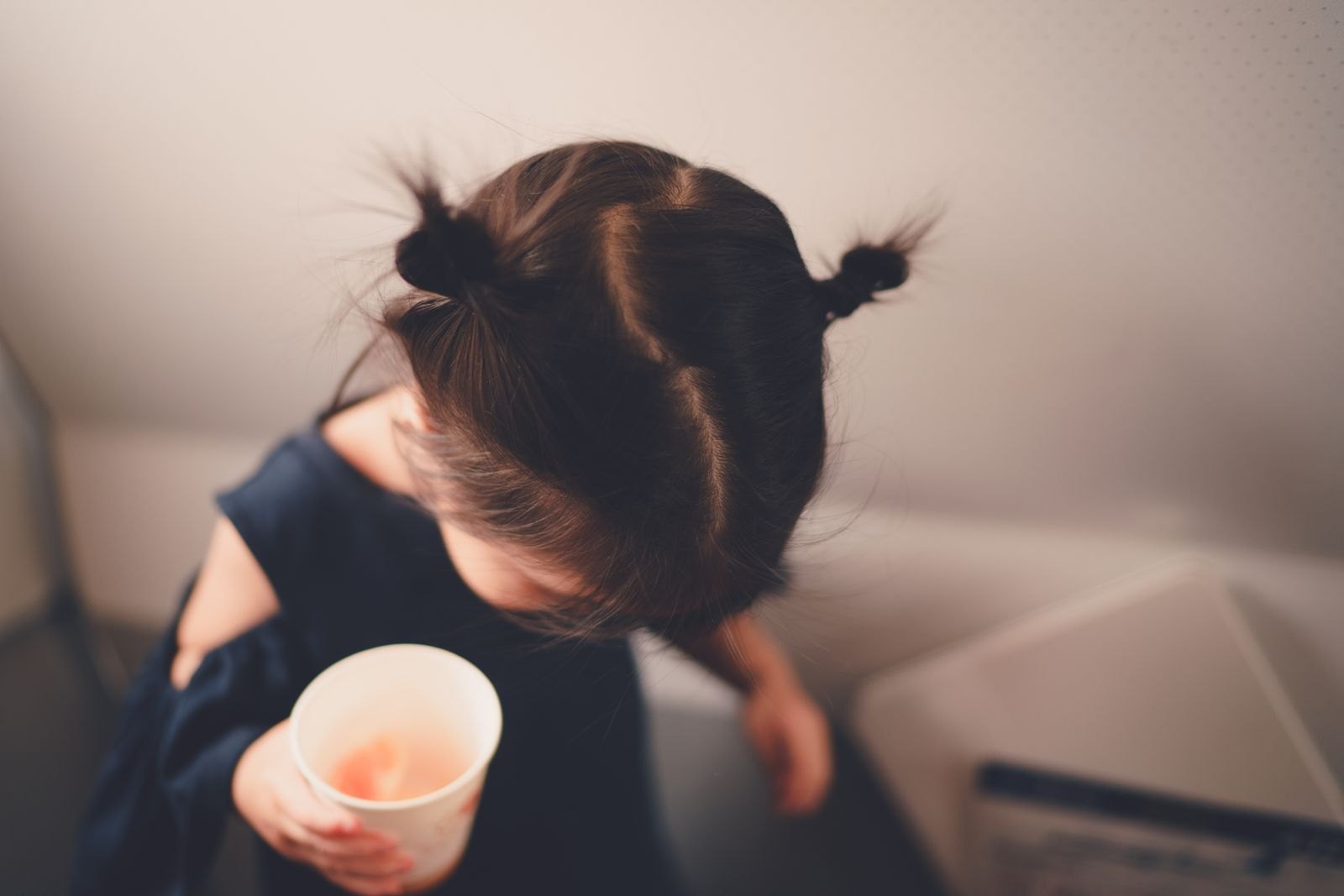 Un niño pequeño sostiene un vaso y se gira hacia otro lado