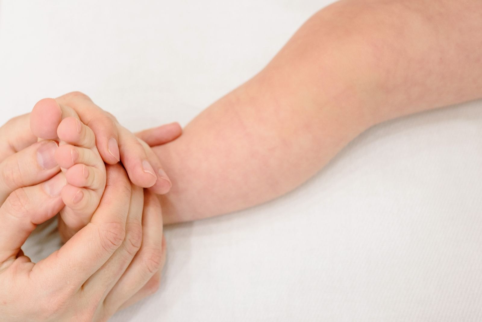 Parent tenant délicatement le bras d'un nouveau-né pour observer sa peau