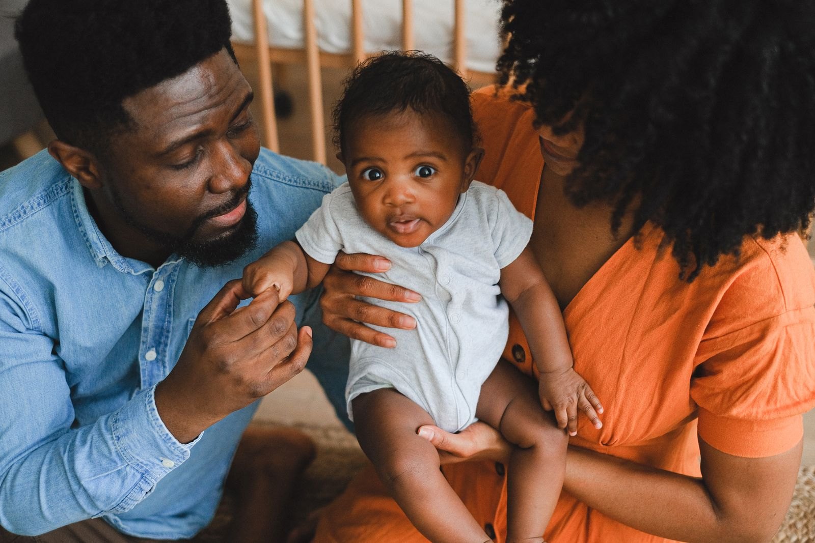 Les deux parents observent leur bébé avec attention, l'un tenant sa main