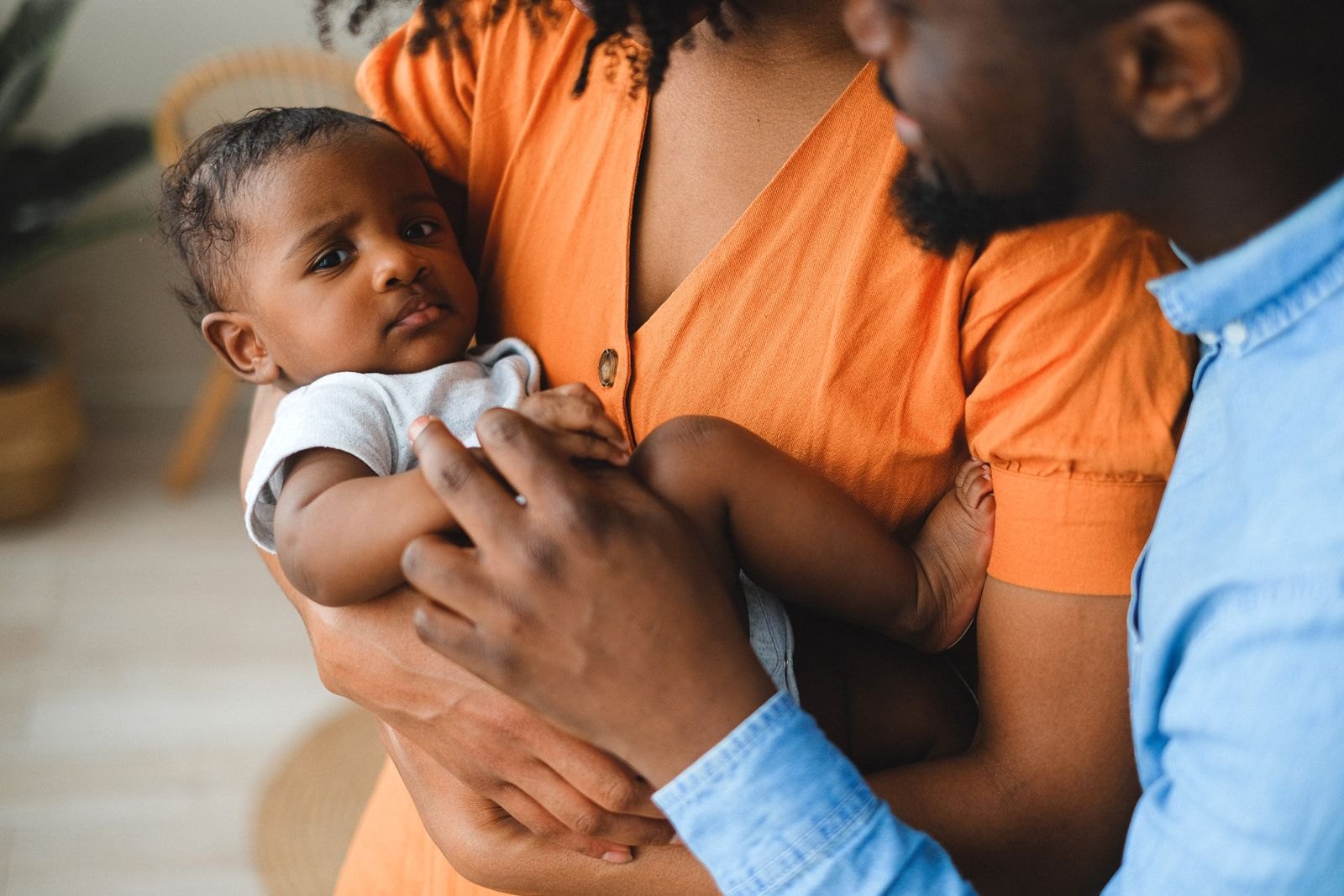 Un bébé au regard sérieux et fixe, porté par ses deux parents