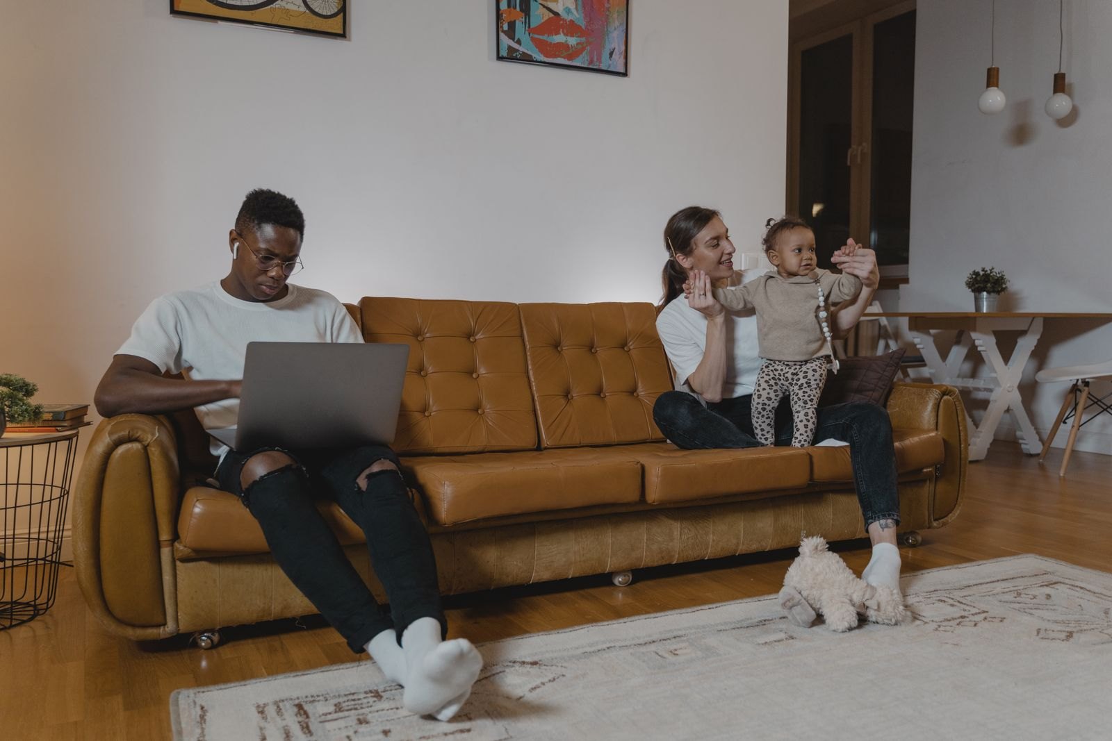 Un père absorbé par son ordinateur portable sur le canapé pendant que la mère joue avec le bébé à côté de lui