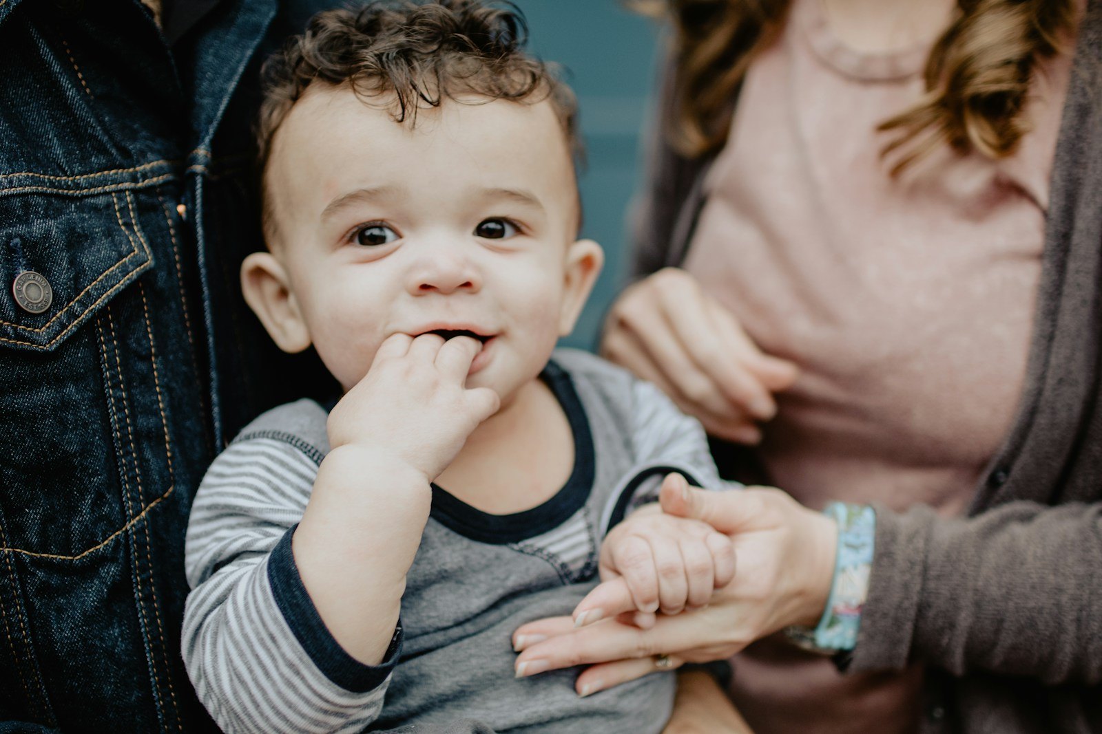 Un bébé assis entre ses deux parents, la main de sa mère tenant doucement la sienne
