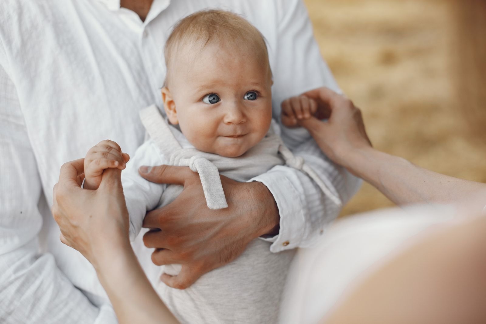 Bébé dans les bras d'un parent, l'air attentif et légèrement méfiant face à quelqu'un hors champ