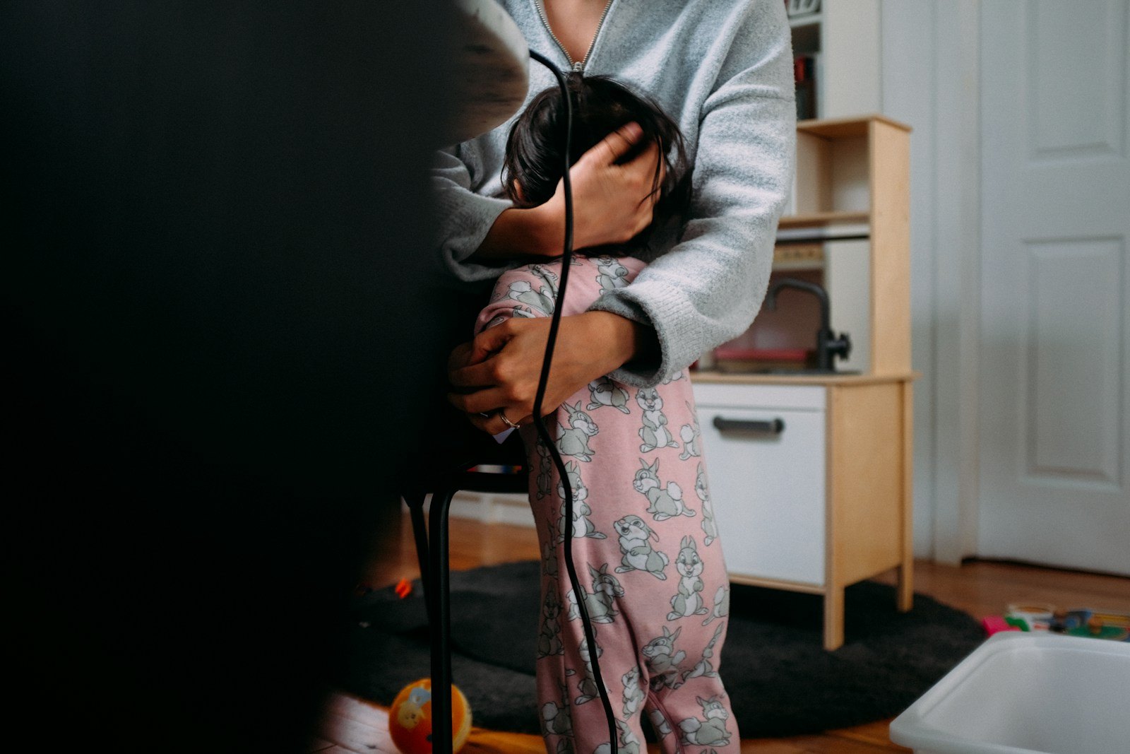 Un parent tient contre lui un bébé apaisé près d'une fenêtre, après un épisode de pleurs