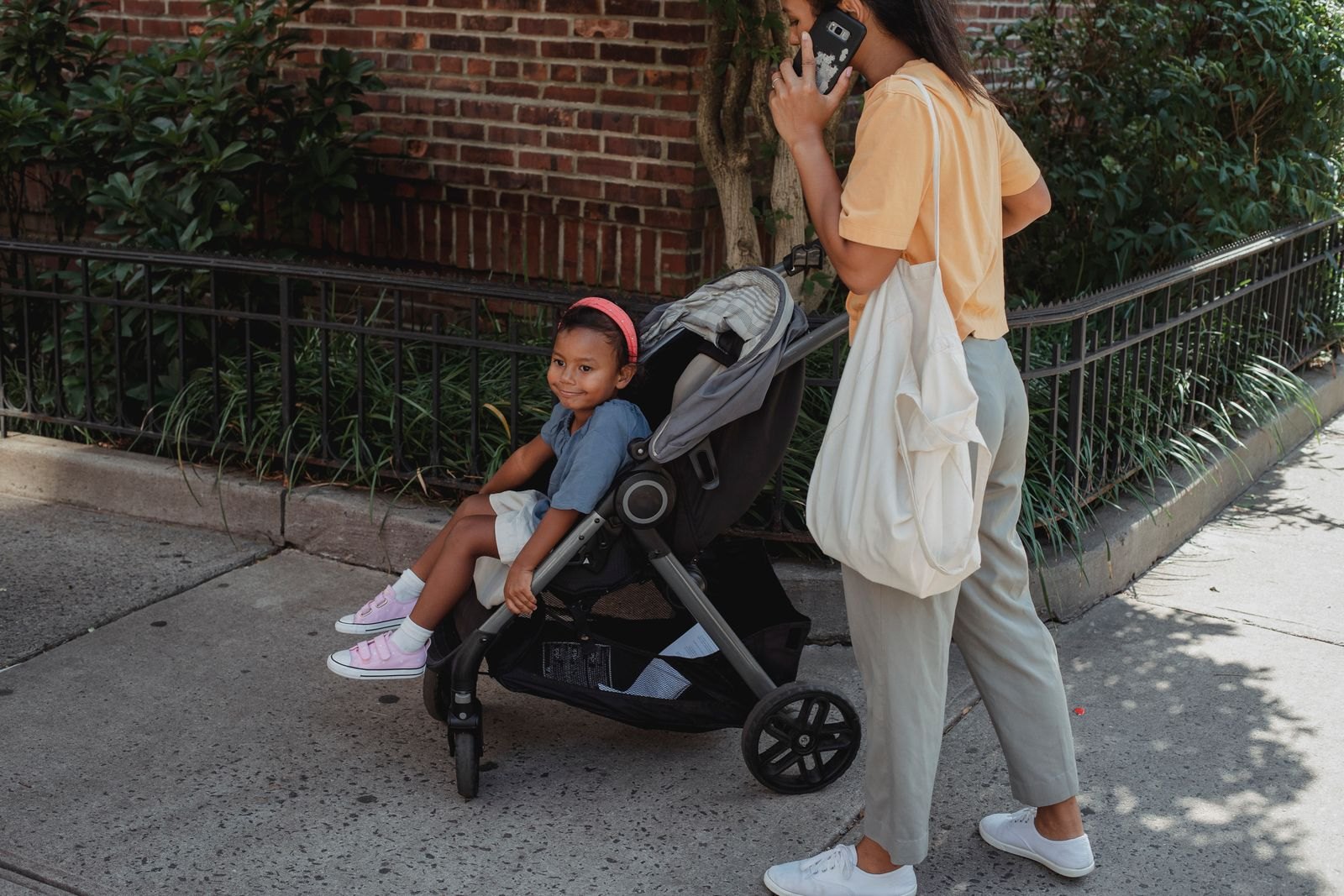 Un parent pousse une poussette dans une rue de ville avec un jeune enfant installé dedans