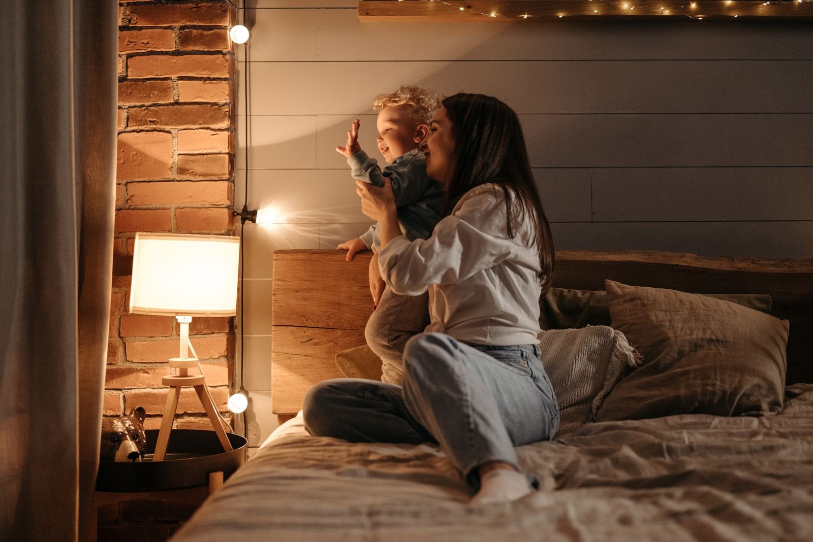 Une mère assise avec son enfant près d'une lampe allumée, dans une chambre calme le soir