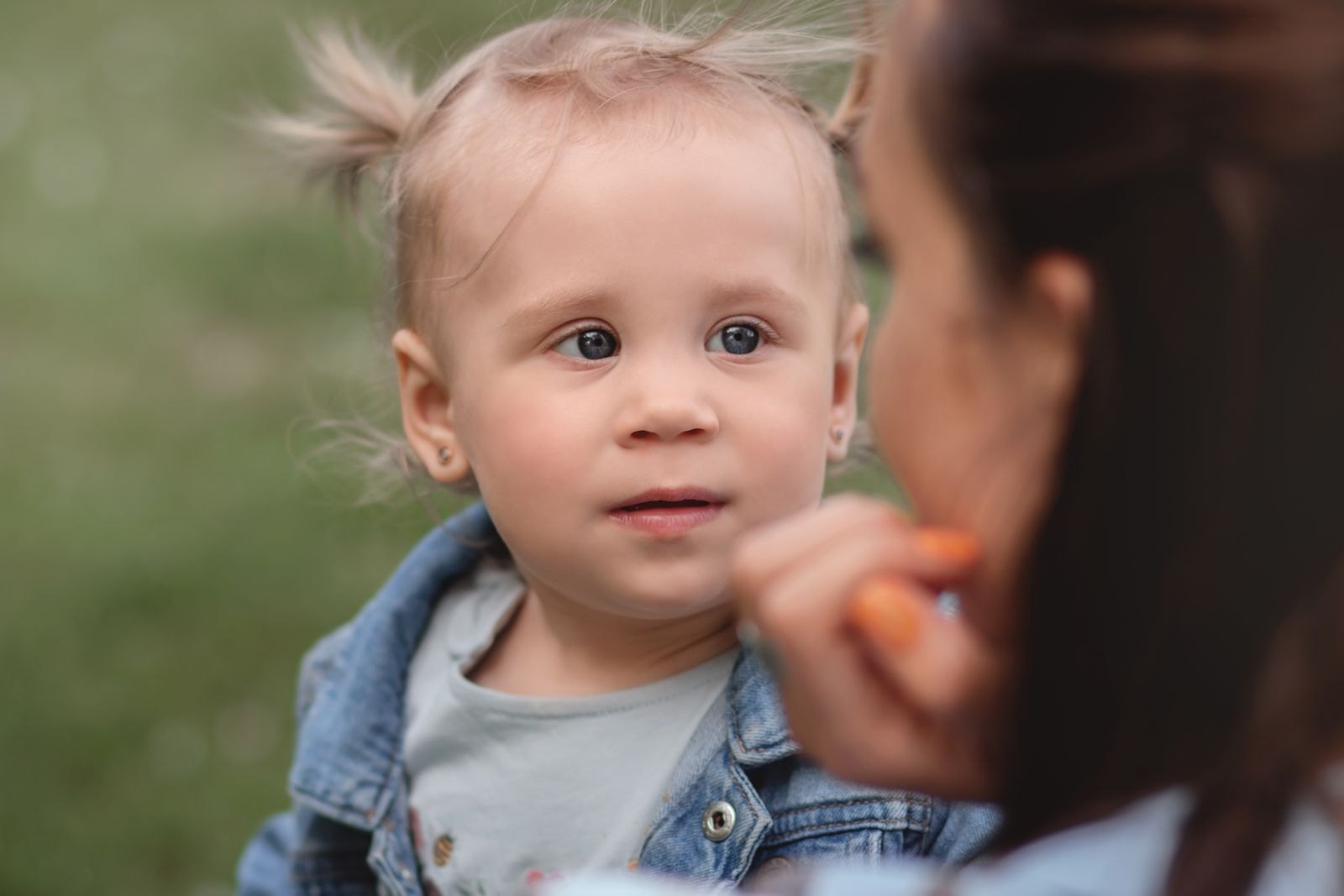 Un genitore accovacciato guarda un bambino piccolo negli occhi mentre gli parla con calma all'aperto