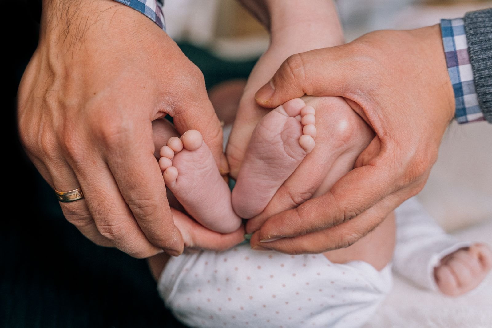 Le mani di un genitore che tengono delicatamente i piedini di un neonato