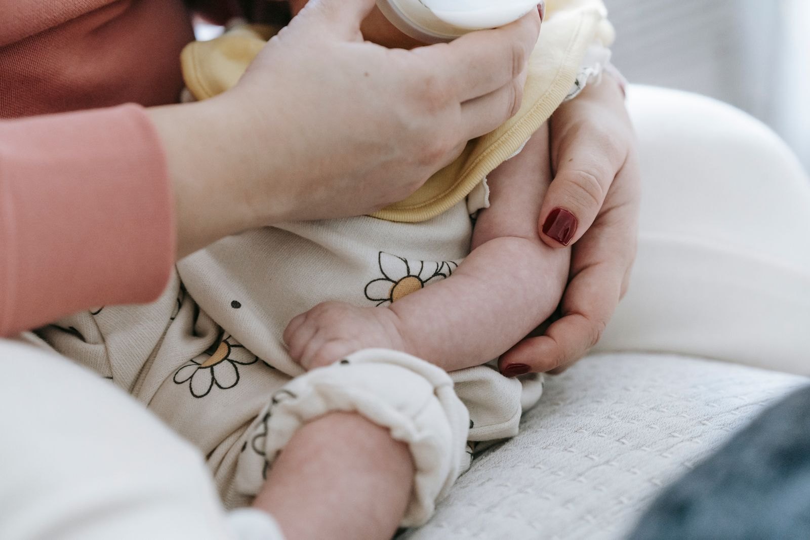 Mani di un genitore che sostengono un biberon vicino a un bambino in braccio