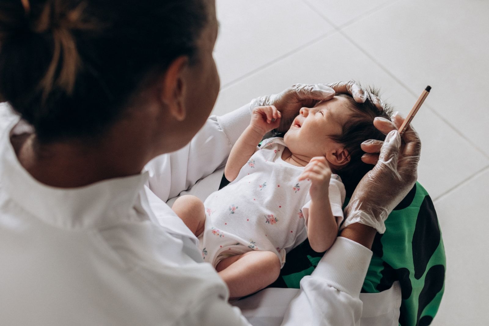 Un pediatra esamina un neonato durante una visita di controllo, con il braccio del bambino sollevato