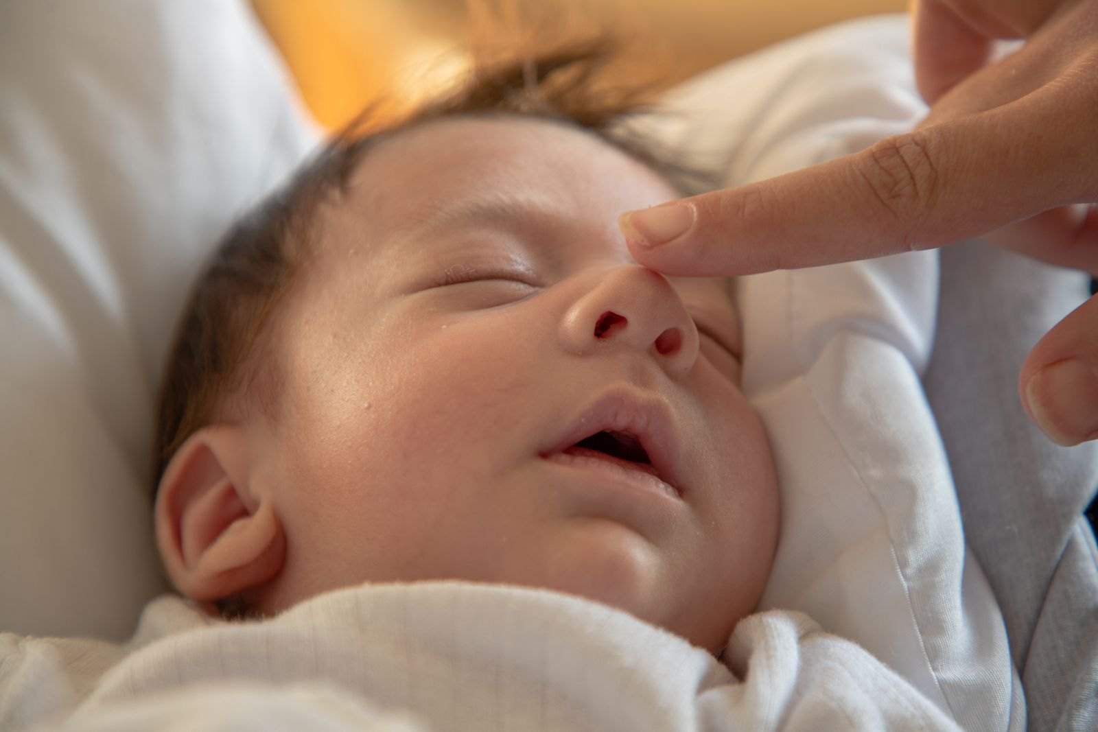 Un genitore accarezza dolcemente il viso di un neonato assonnato mentre si addormenta