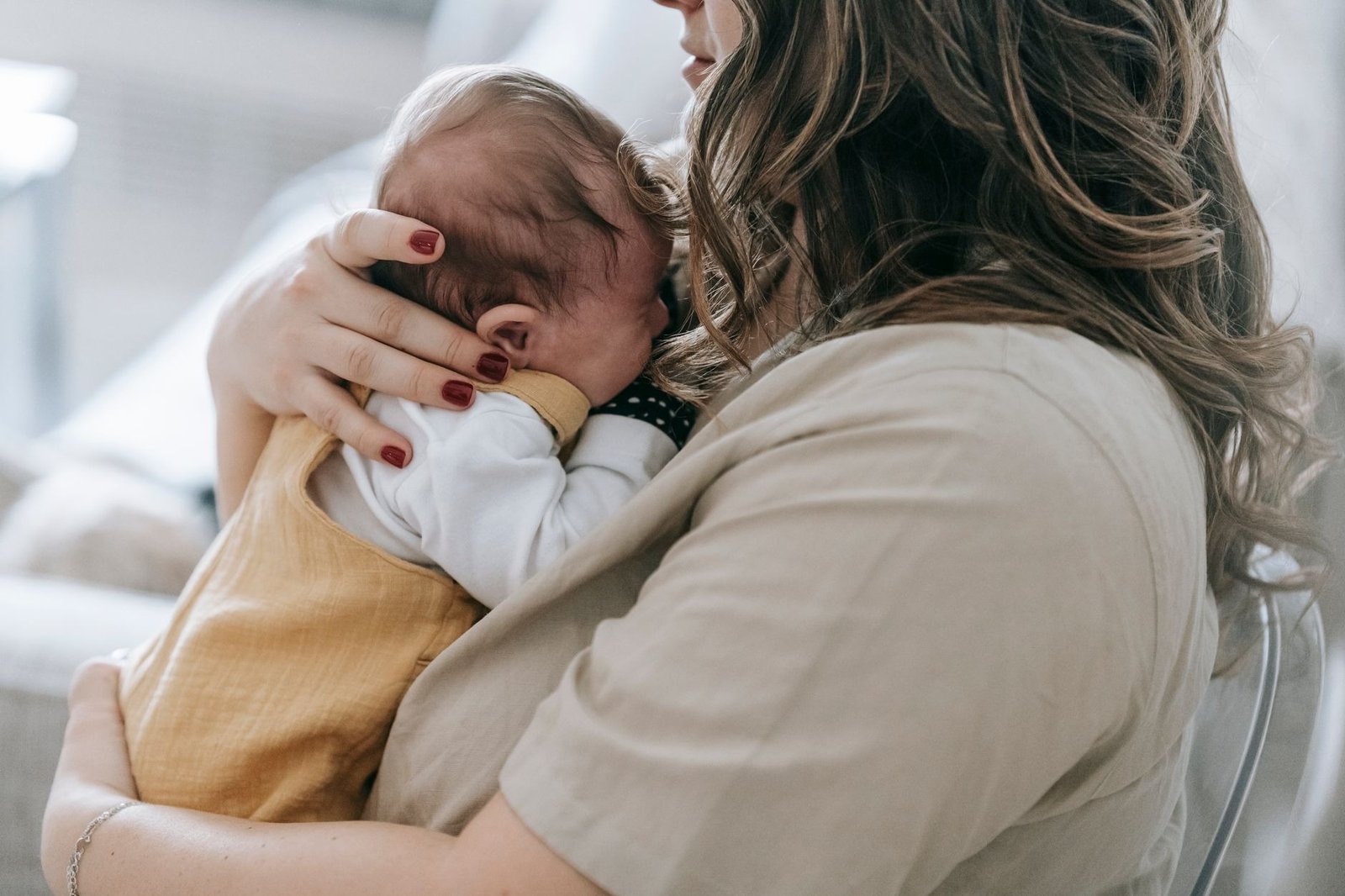 Un genitore che tiene il neonato appoggiato alla spalla dopo la poppata per farlo ruttare