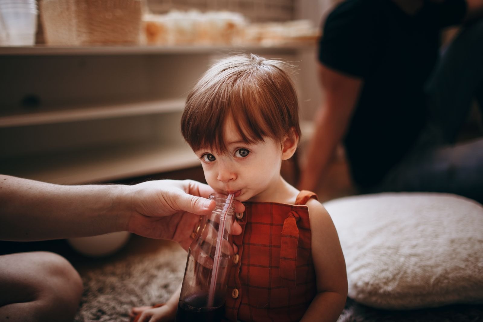 Bambino piccolo che beve tenendo in mano un biberon con cannuccia