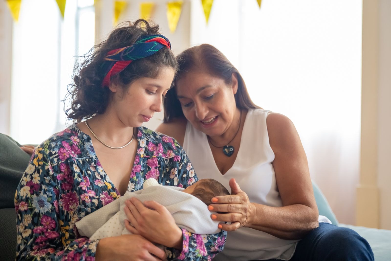 Una neomamma e un neopapà mostrano il loro neonato alla nonna, che lo osserva con affetto