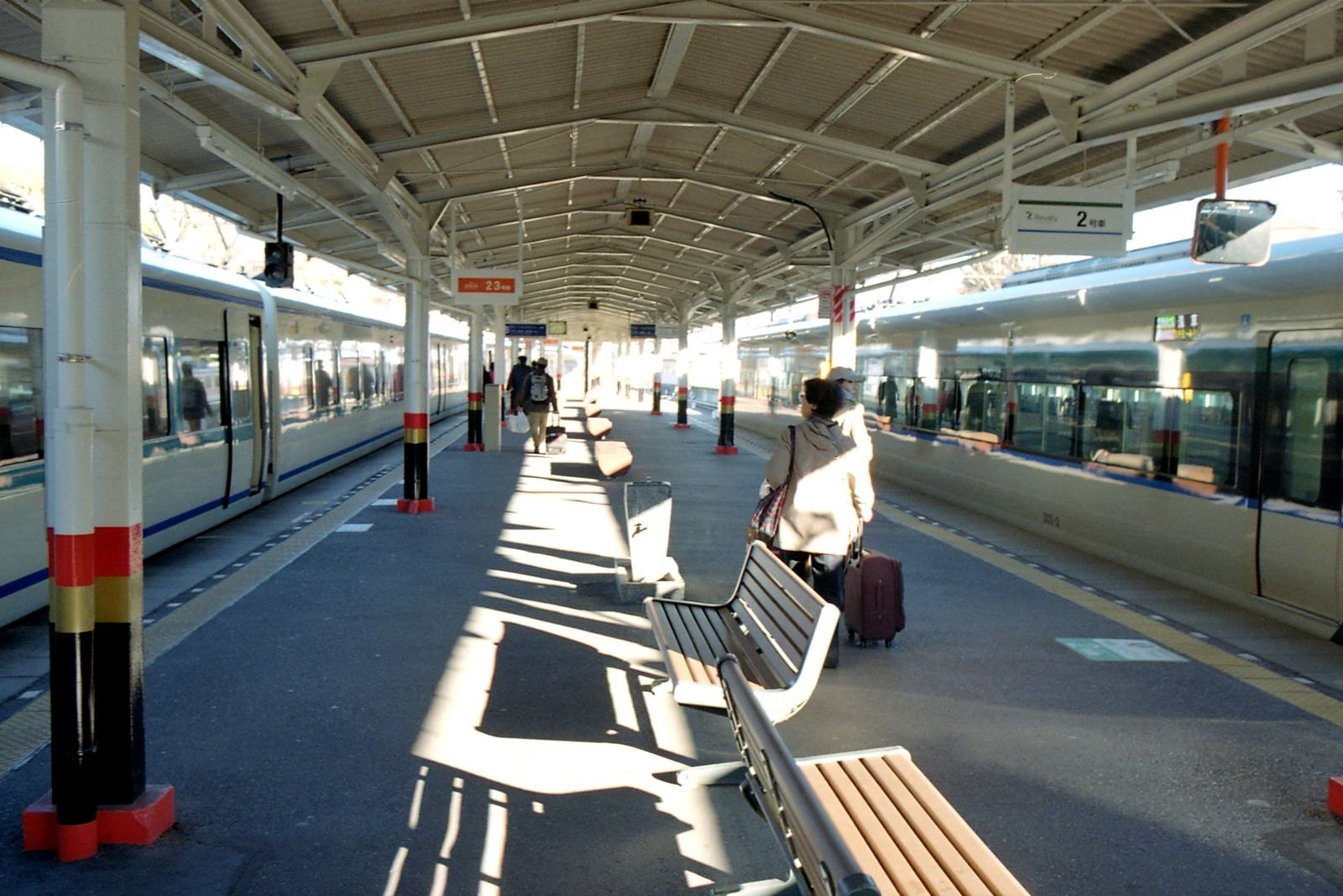 日本の駅のホームで電車を待つ人たち