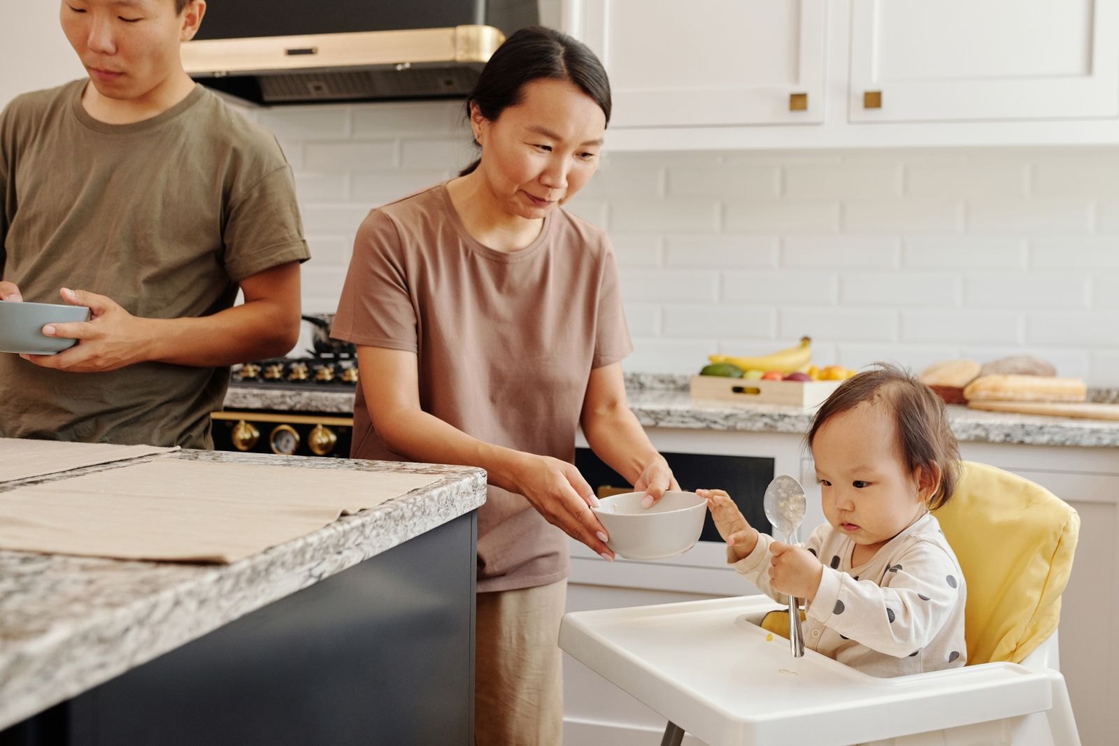 両親が幼児に食事のお椀を手渡している様子