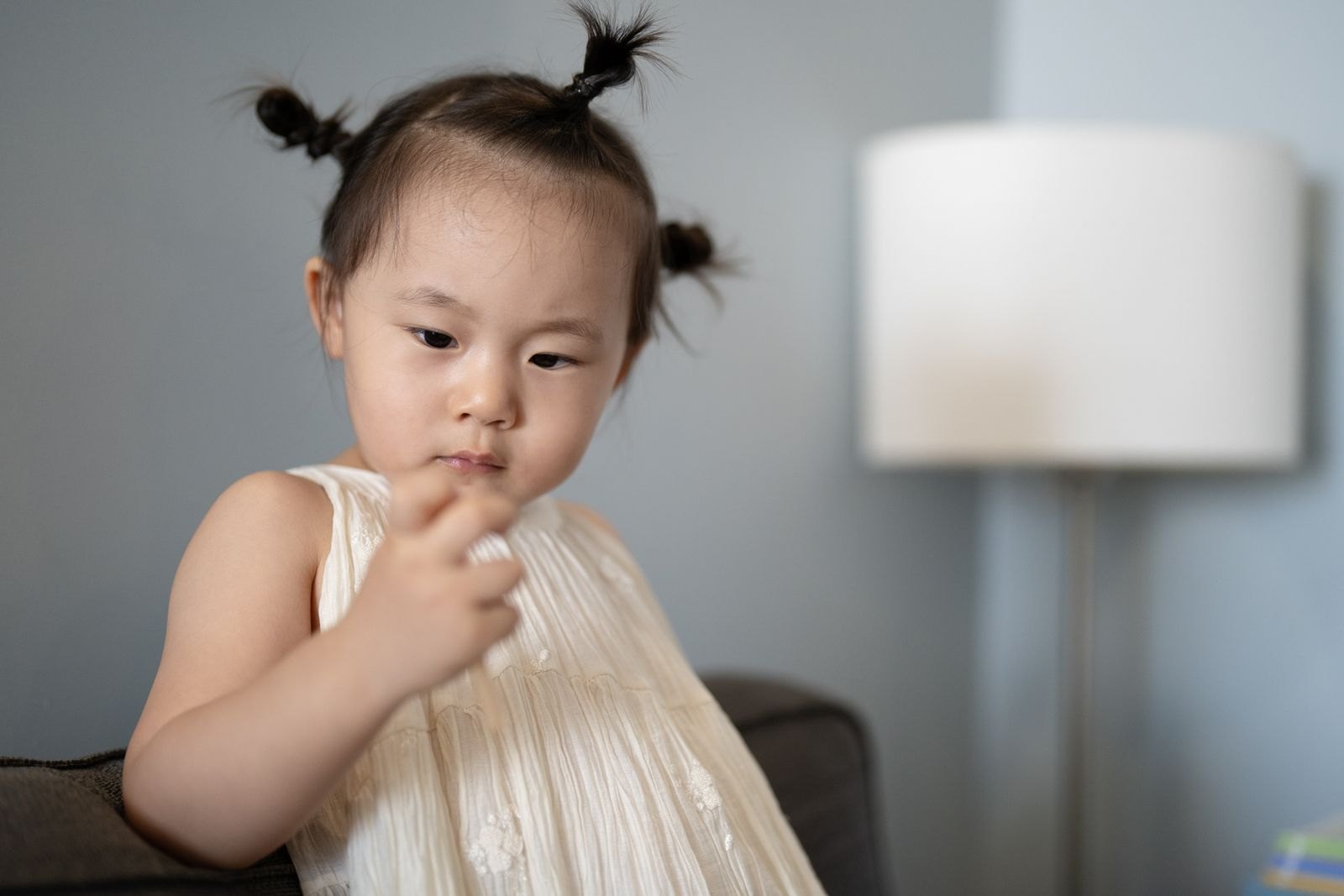 실내에서 손을 입가에 대고 서 있는 아이