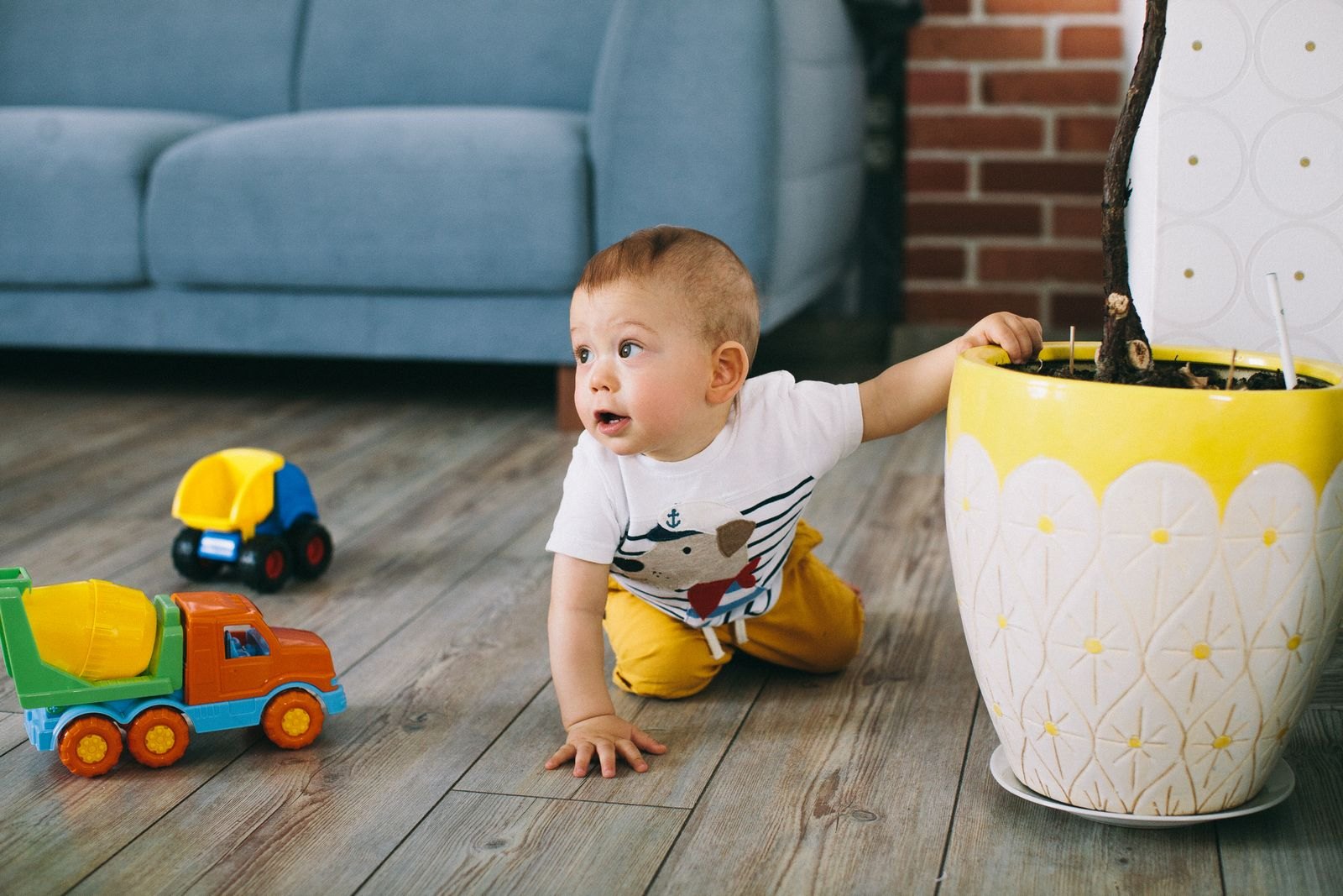 Baby op handen en knieën op de vloer, alert opzij kijkend naar iets buiten beeld