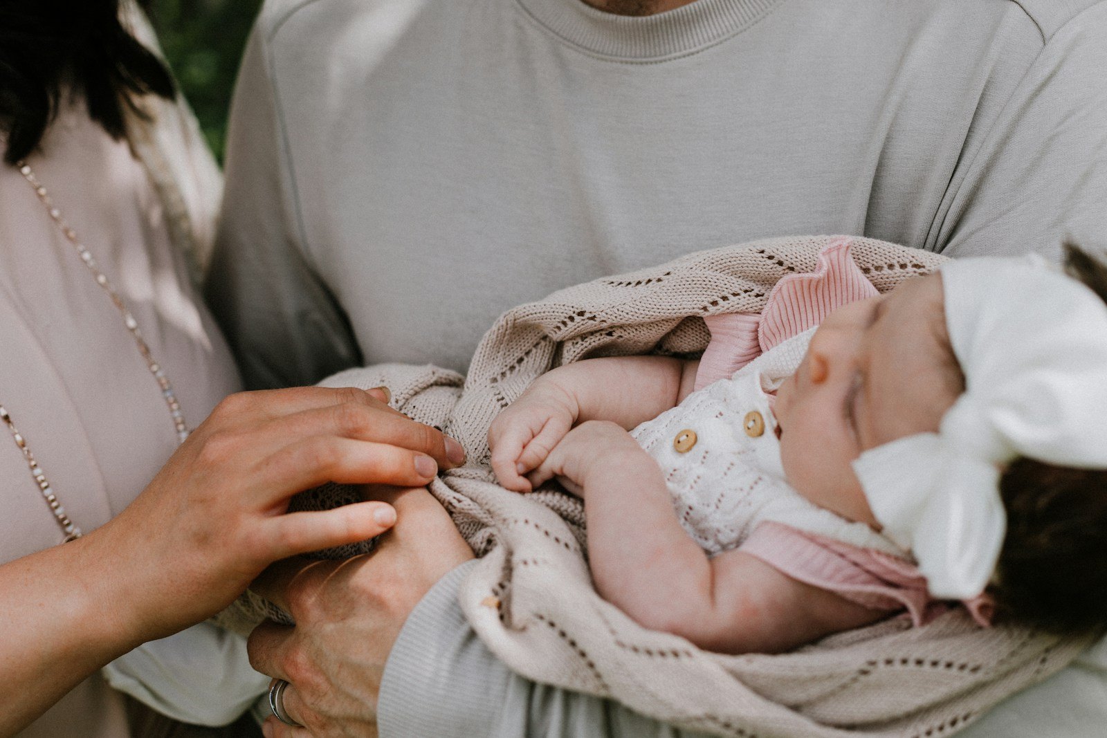 Twee ouders houden samen hun pasgeboren baby dicht tegen zich aan