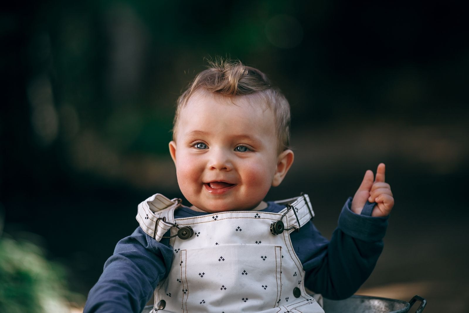 Een baby steekt lachend een vinger op, een vroege vorm van gebaren