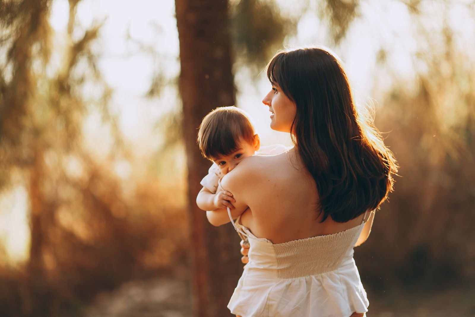 Een moeder draagt haar baby, die waakzaam over haar schouder naar buiten kijkt