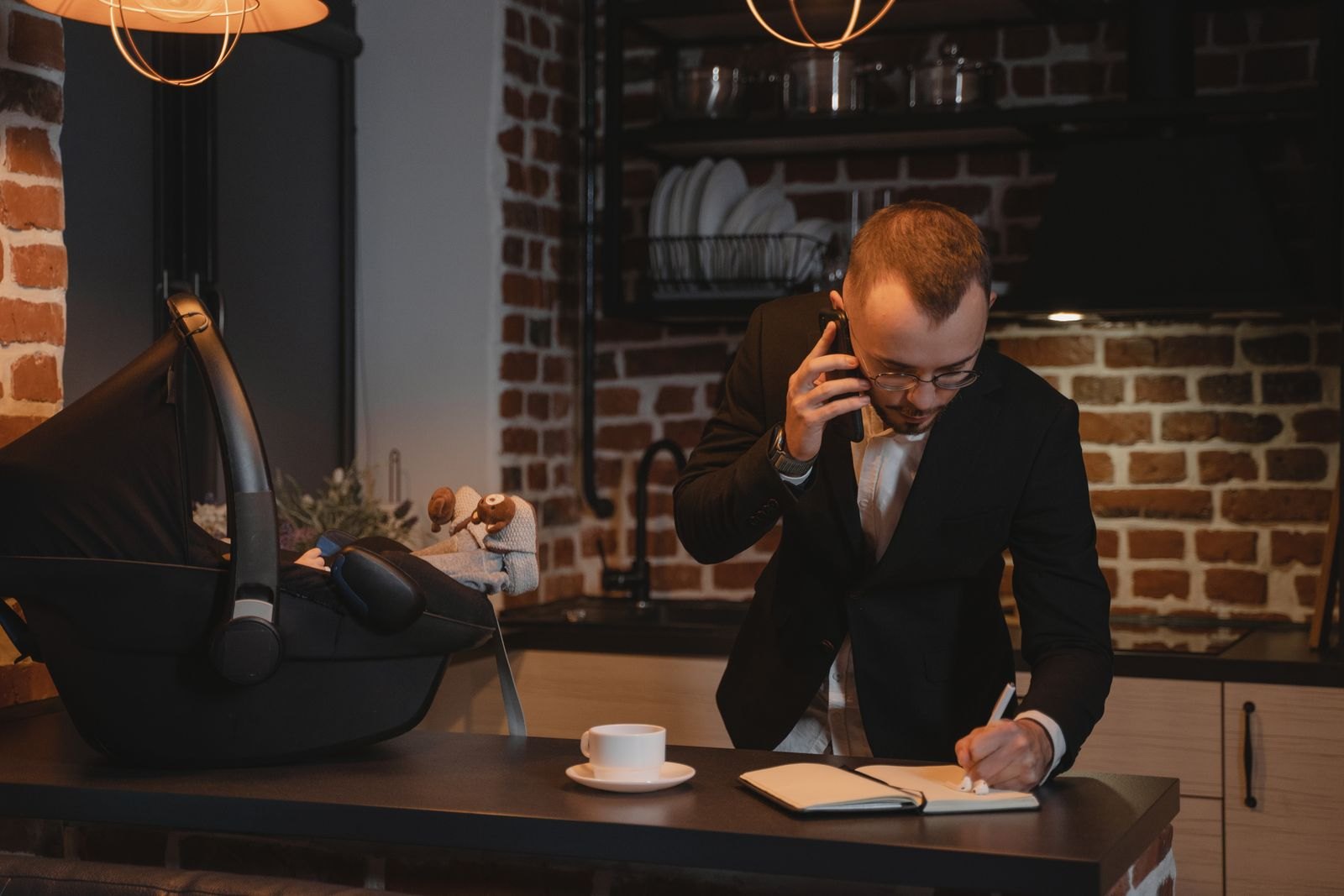 Een man in pak belt terwijl hij met een laptop in een hotellounge zit, tijdens een zakenreis