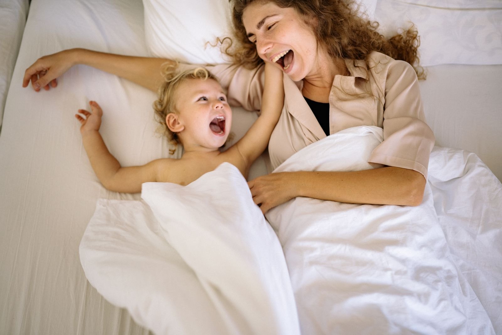 Een ouder en een peuter lachen samen wakker in bed vroeg in de ochtend